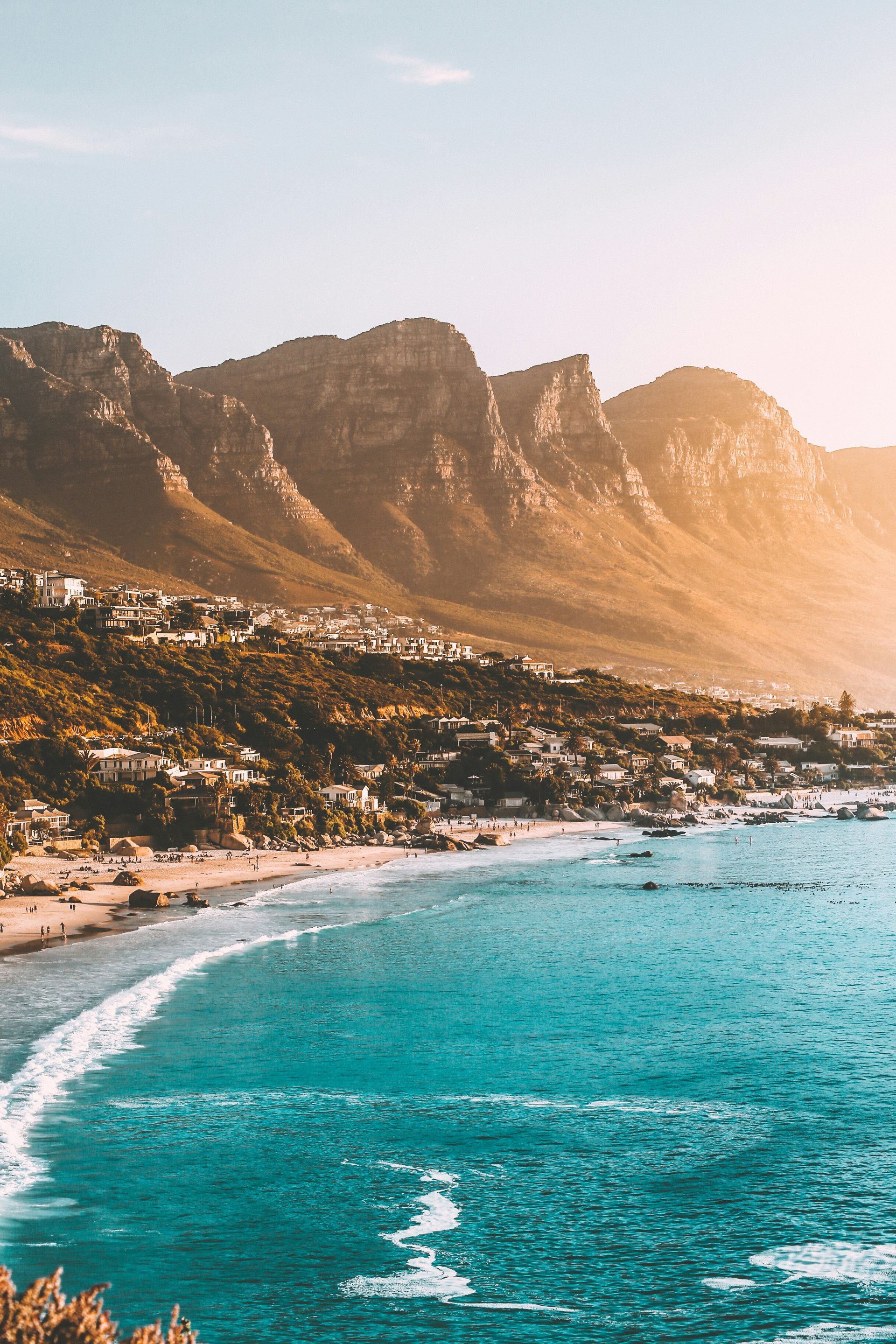 City of Cape Town on the ocean coastline with teal water and sunlit mountainside in South Africa.