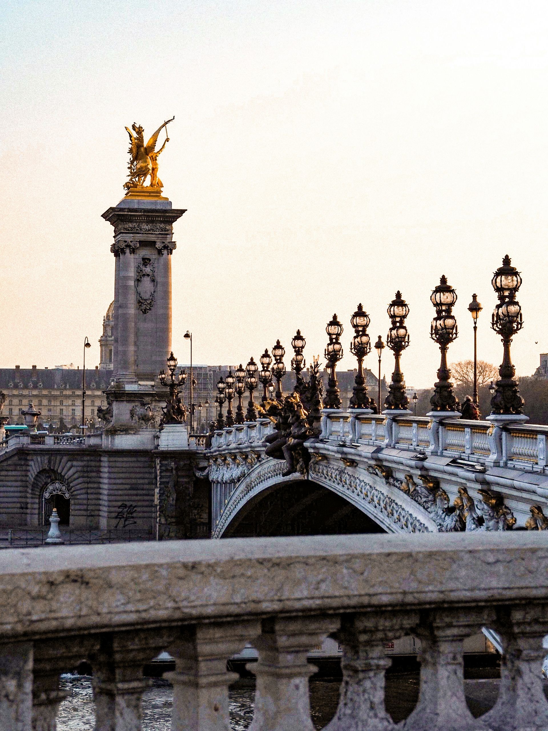 The Pont Alexandre III bridge with a statue on top of it in the middle of it in Paris, France.