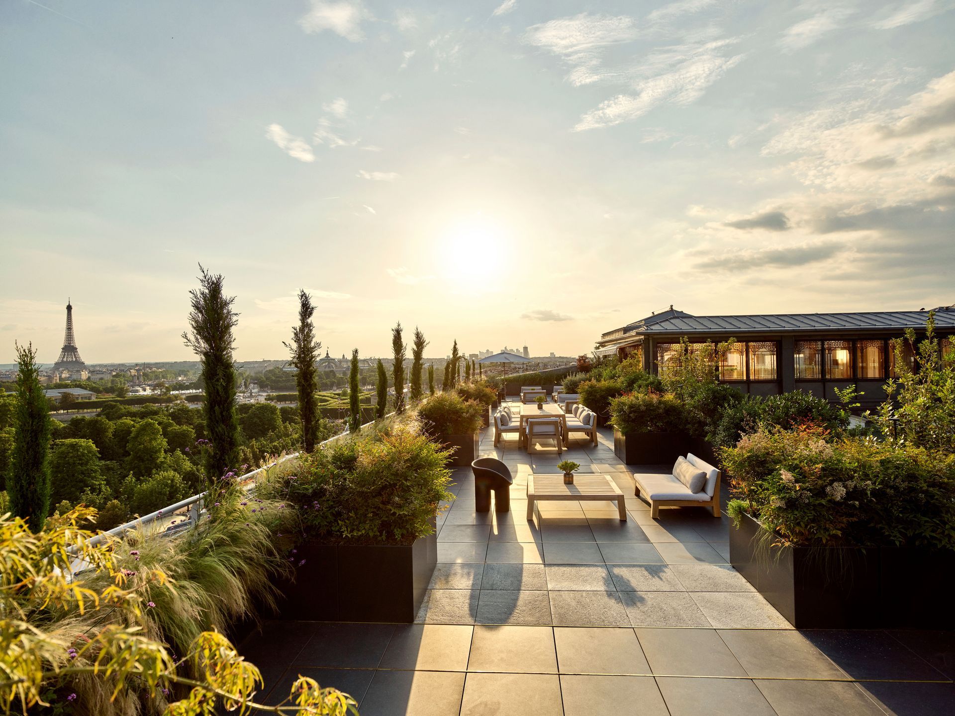 A rooftop terrace with a view of Paris at sunset at Dorchester Collection Hotel.