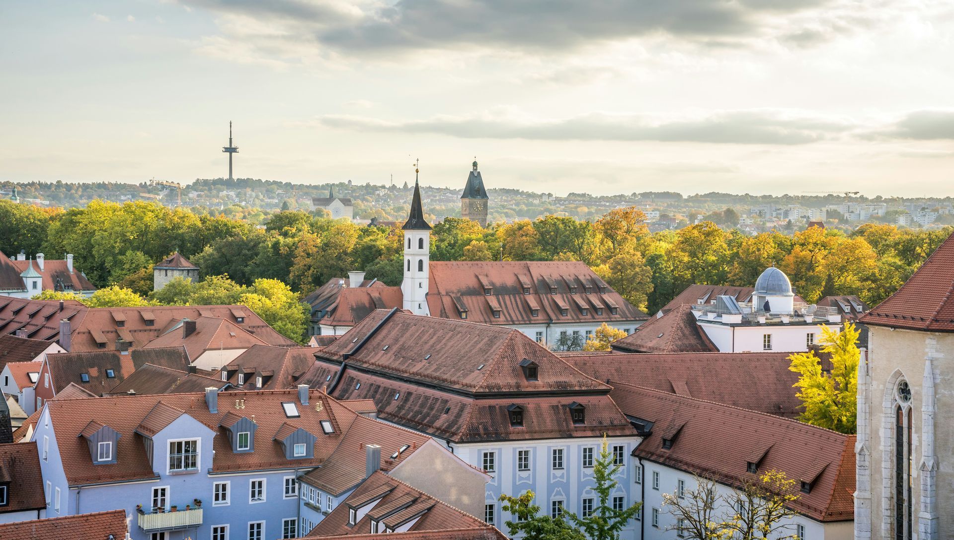 An aerial view of a city with red tiled roofs and trees in the background in Nuremberg, Germany.