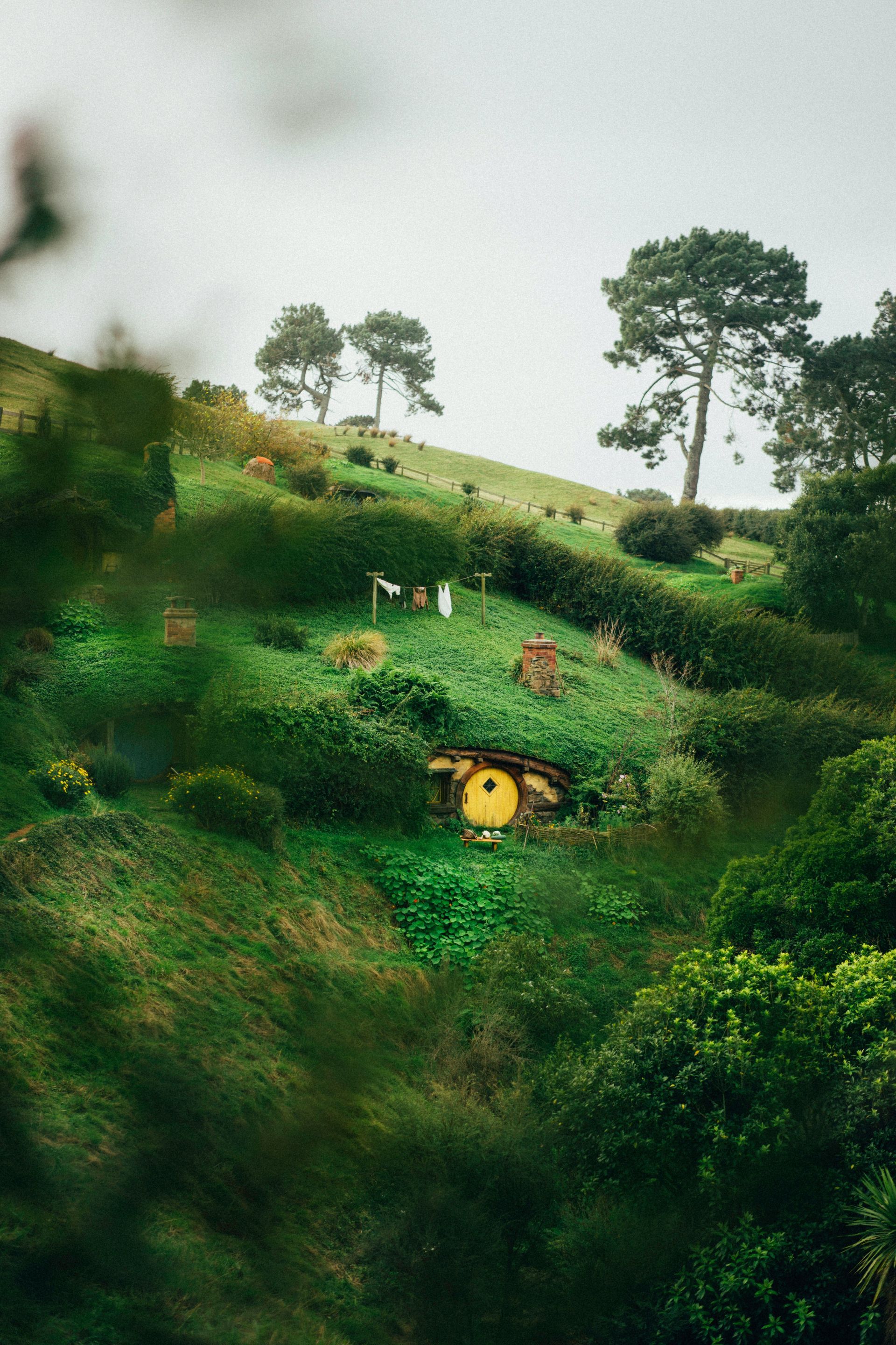A small house is inside a hill surrounded by trees at the Hobbiton Movie Set in Matamata, New Zealand.