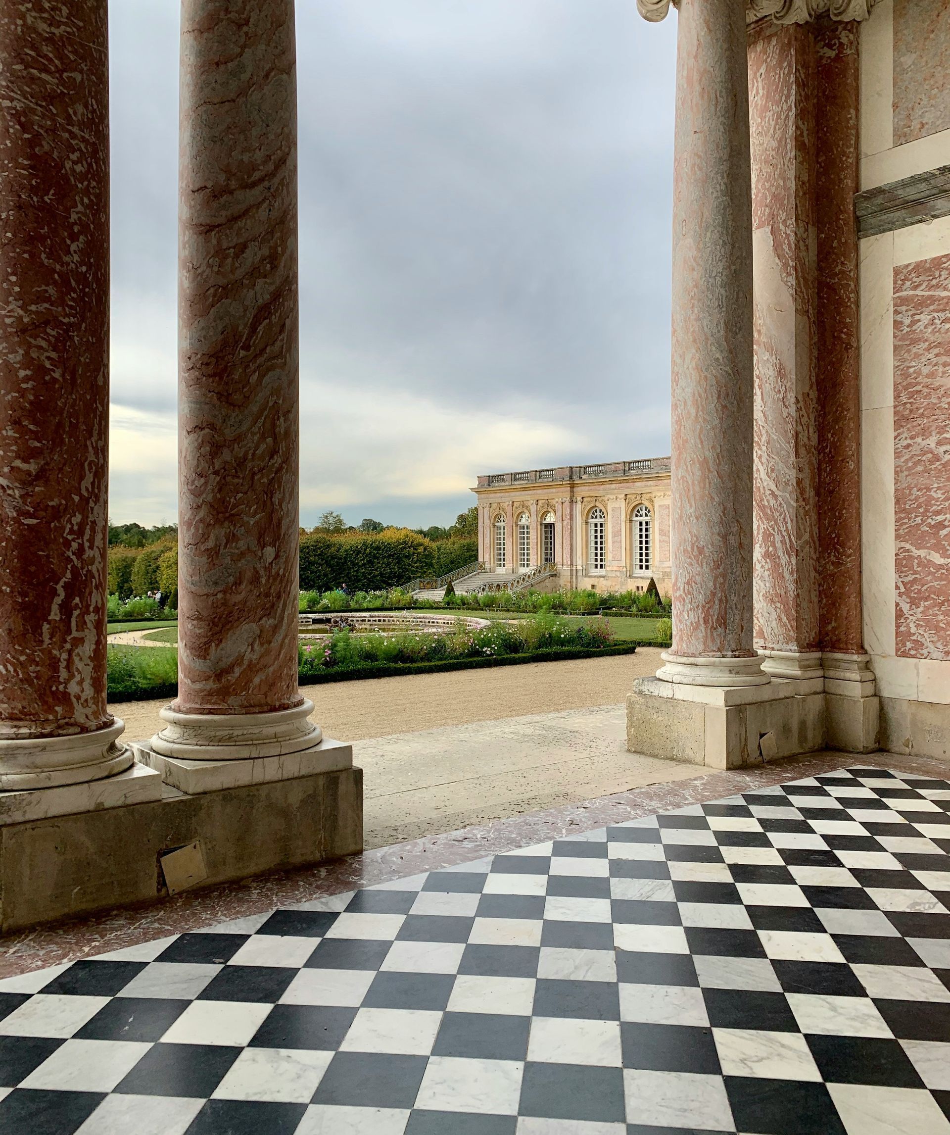 A black and white checkered floor with columns in the background at the Château de Versailles, France.