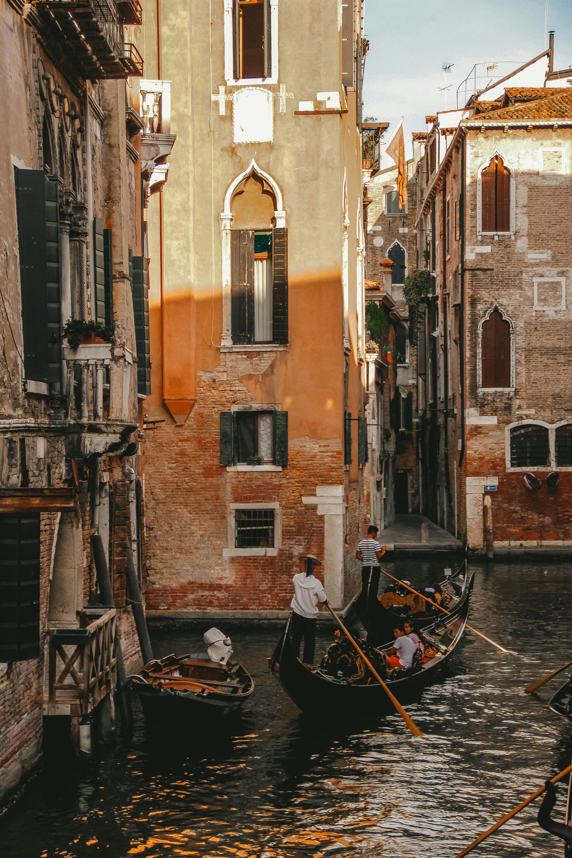 A group of people are riding a gondola down a canal in Venice.