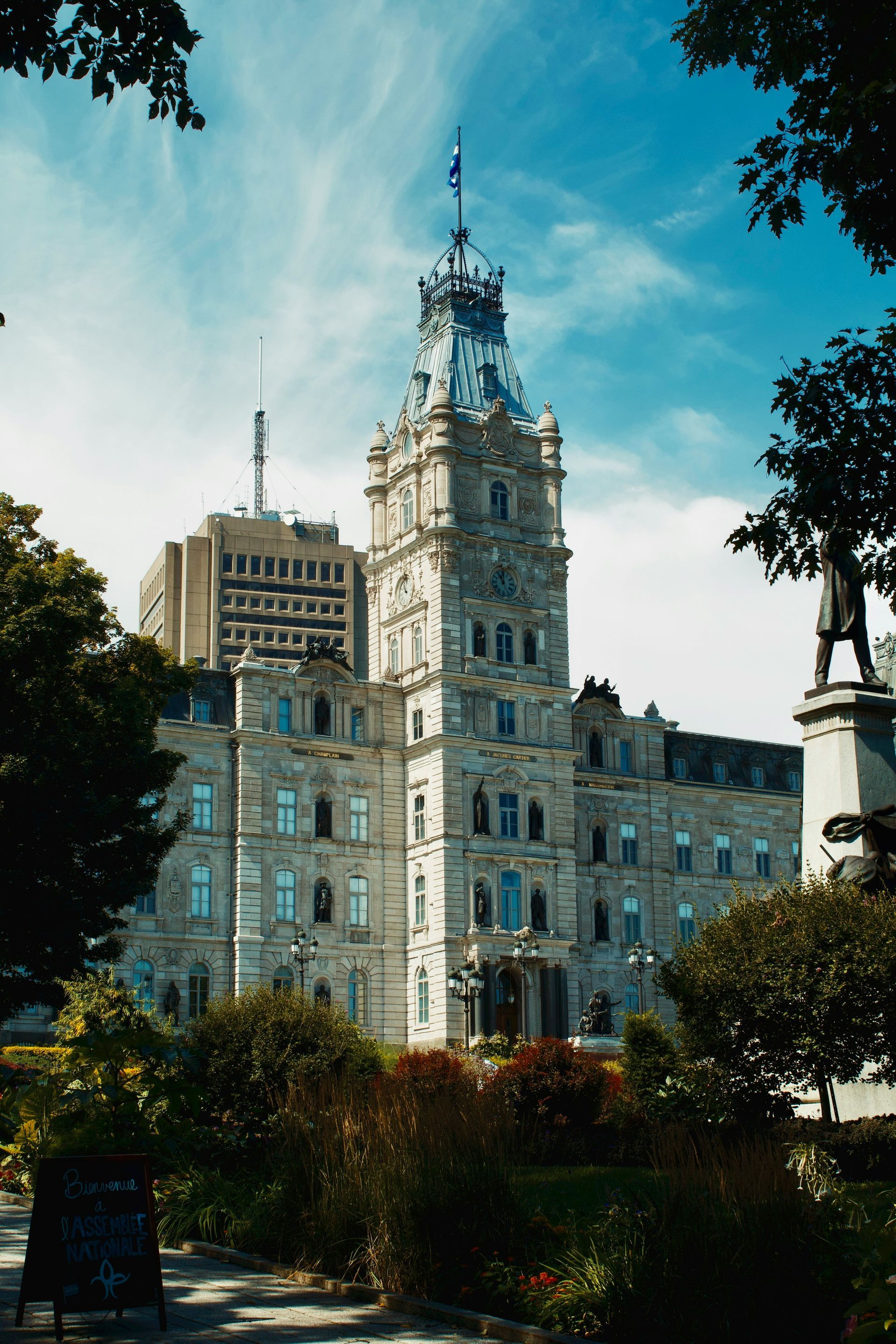 Parliament Building, Quebec City, Canada, viewed from a park with a statue; the ornate stone building has a tall tower.