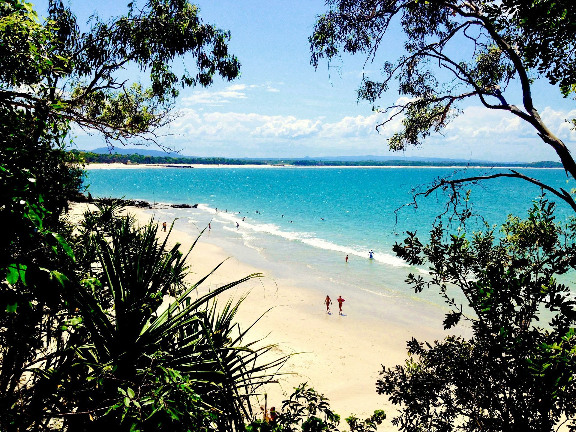 Two people are walking on a beach with a blue ocean in the background in Gold Coast, Australia.