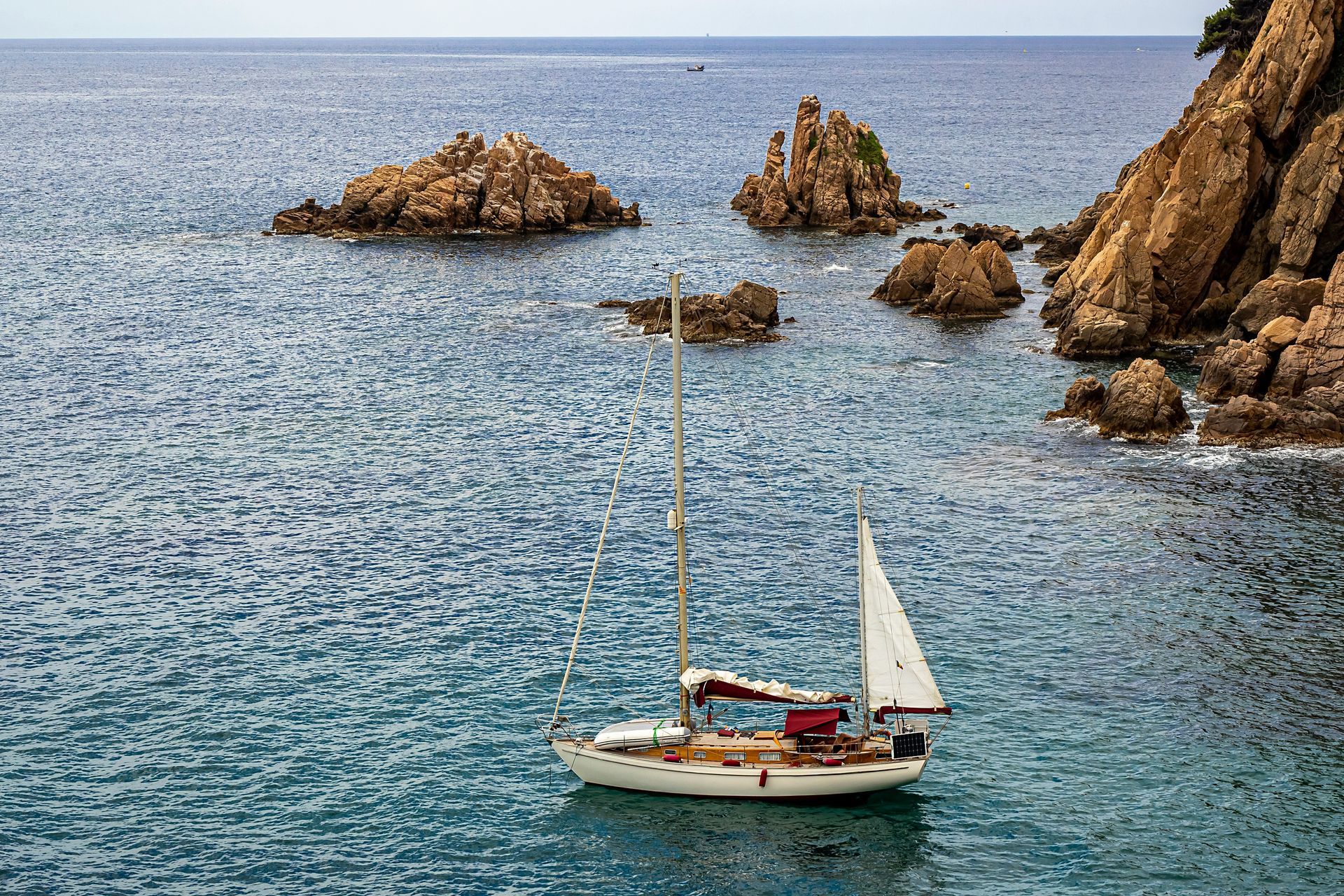 A sailboat is floating on top of a body of water in Blanes, Spain.