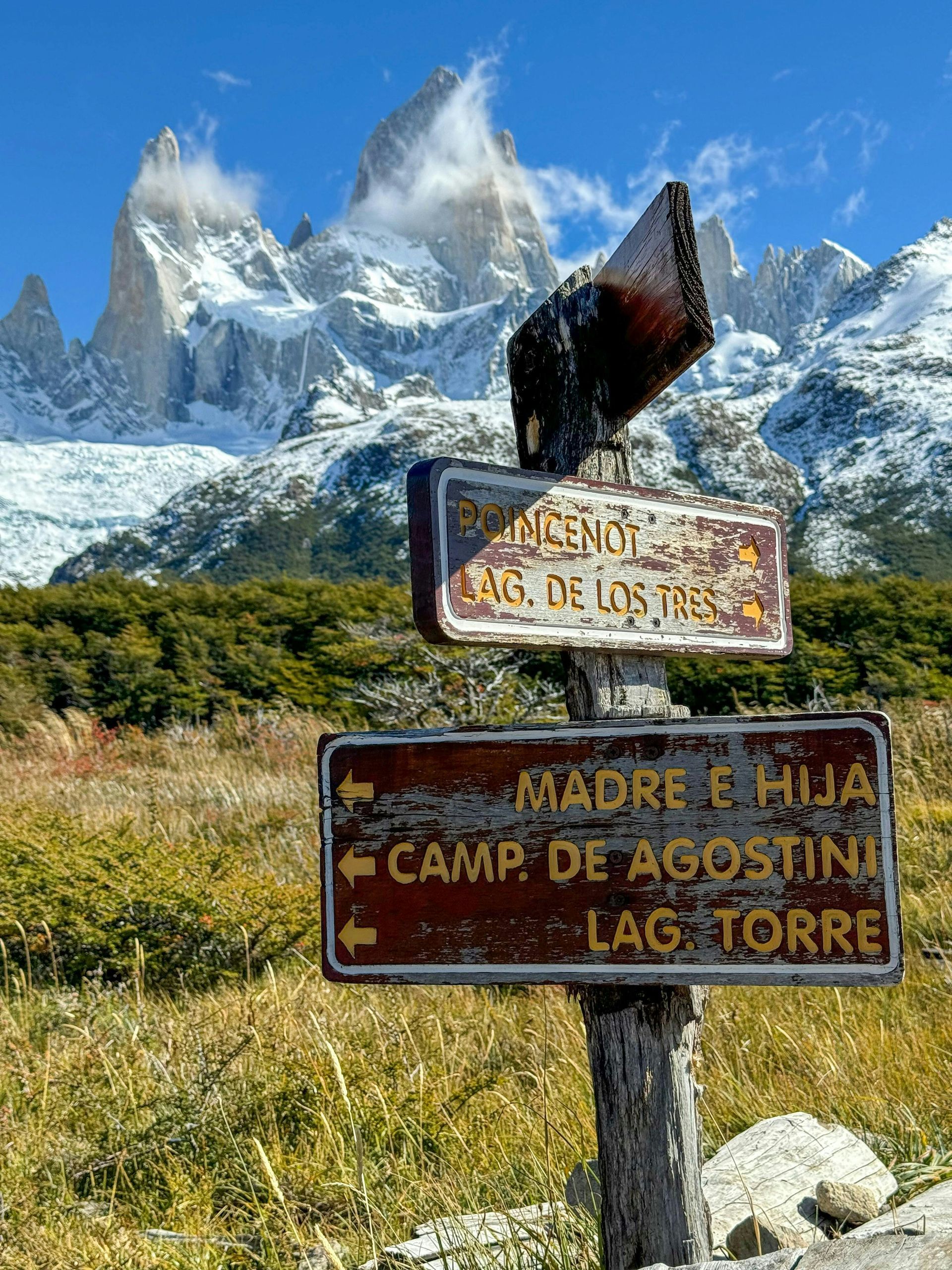 Signpost in front of snow-capped mountains and green landscape at Parque Nacional Los Glaciares in El Calafate, Argentina.