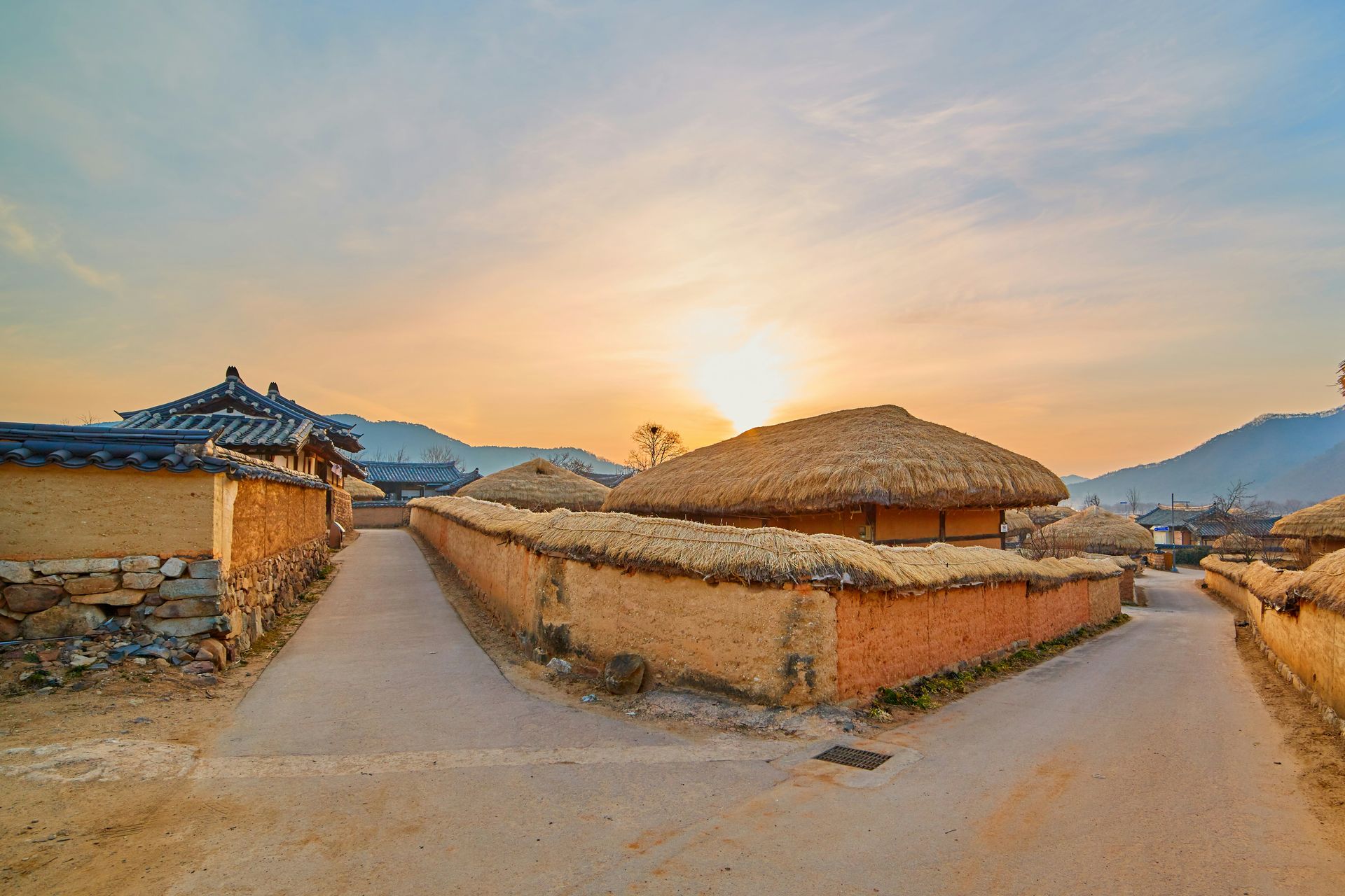 Andong Hahoe Folk Village with thatched-roof houses and earthen walls at sunset in South Korea.