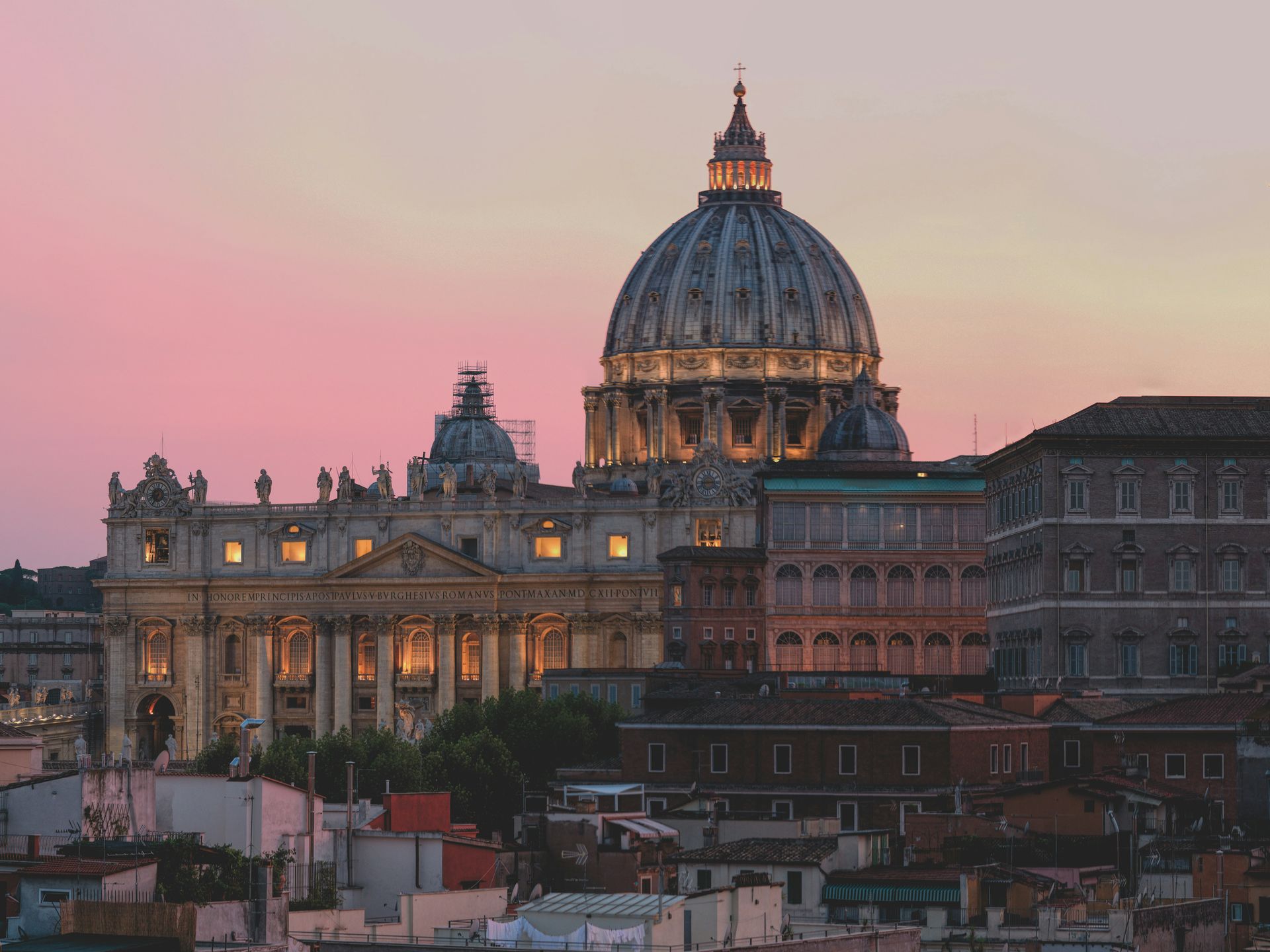 The dome of St. Peter's Basilica is lit up at sunset in Rome.