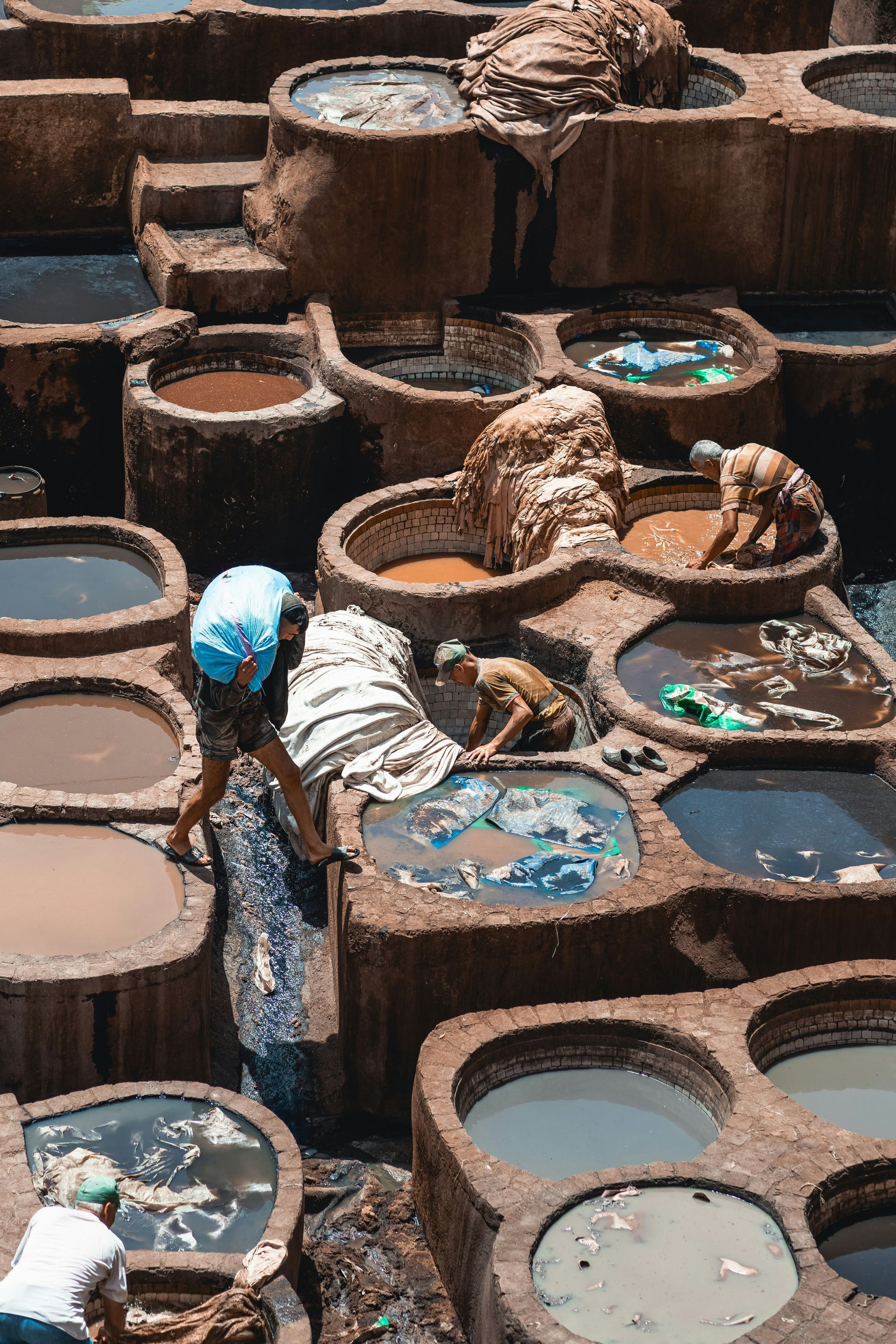 A group of people are working in a Tannery with colorful pools in Fes, Morocco.