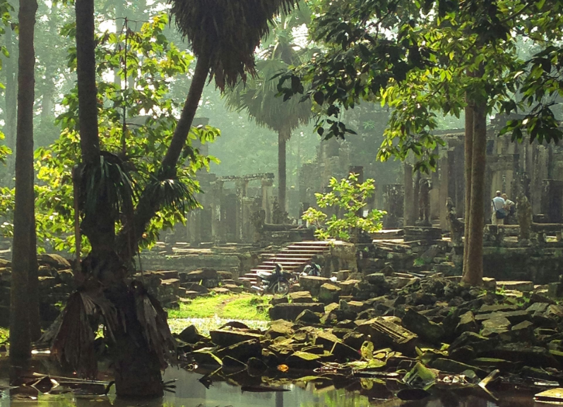 Ancient temple ruins overgrown with trees, steps leading up in Cambodia.