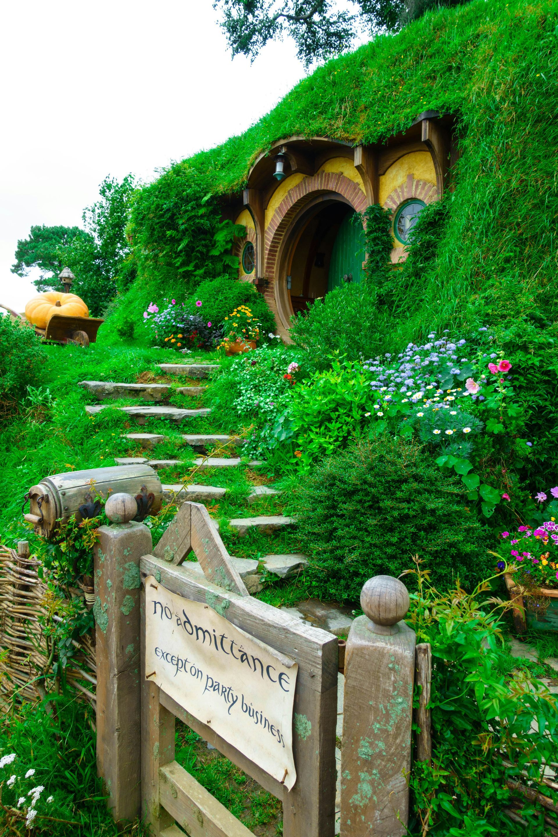 A hobbit house on top of a hill with stairs leading up to it at the Hobbiton Movie Set in Matamata, New Zealand.