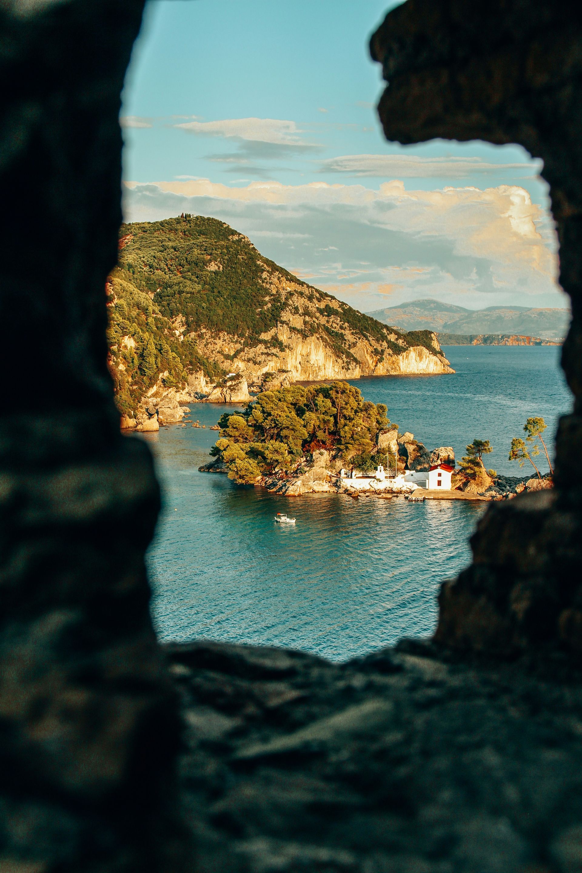 A view of a small island in the middle of the ocean through a window in Parga, Greece.