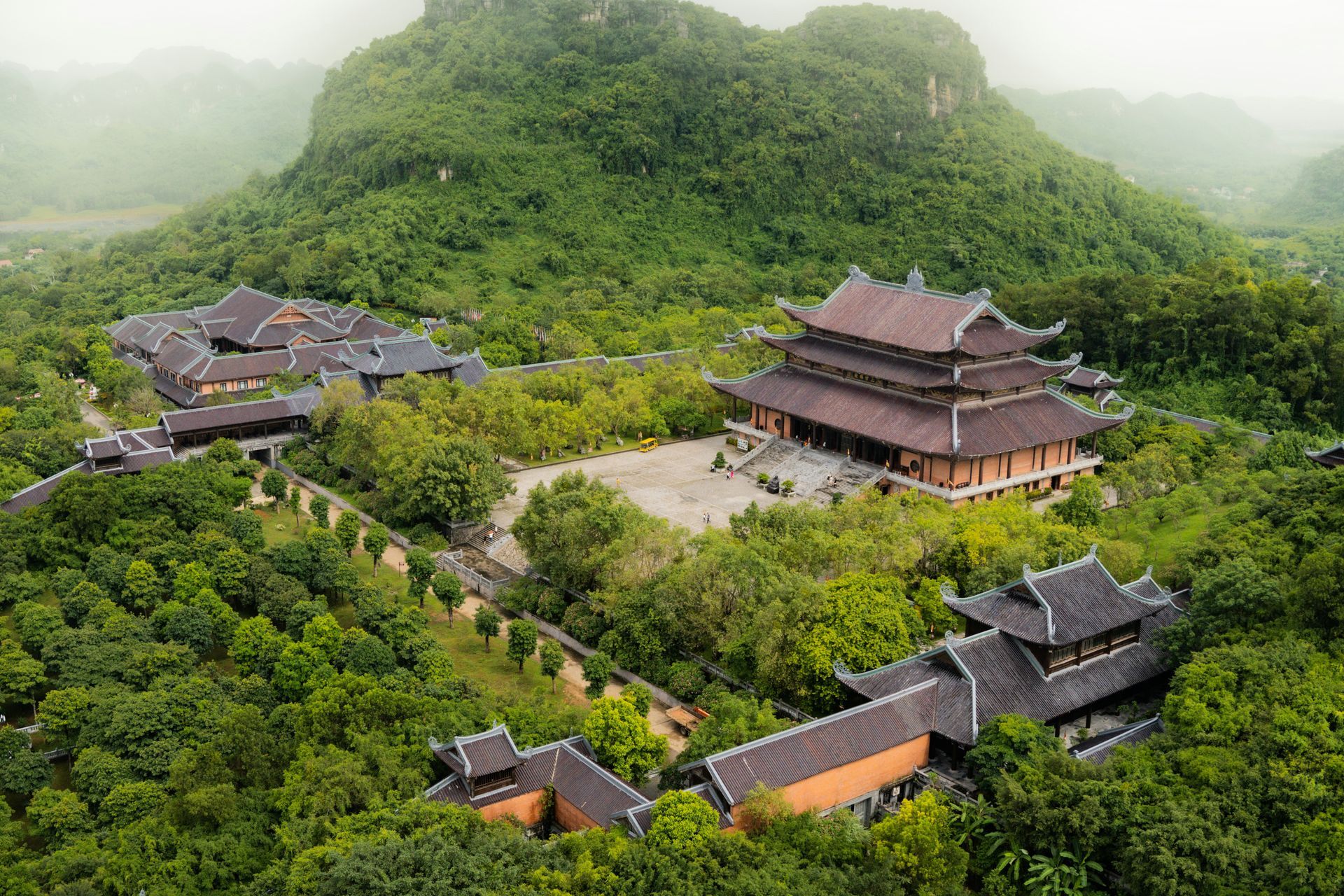 Temple complex nestled in lush, green landscape with mountains in the background in Ninh Bình, Vietnam.