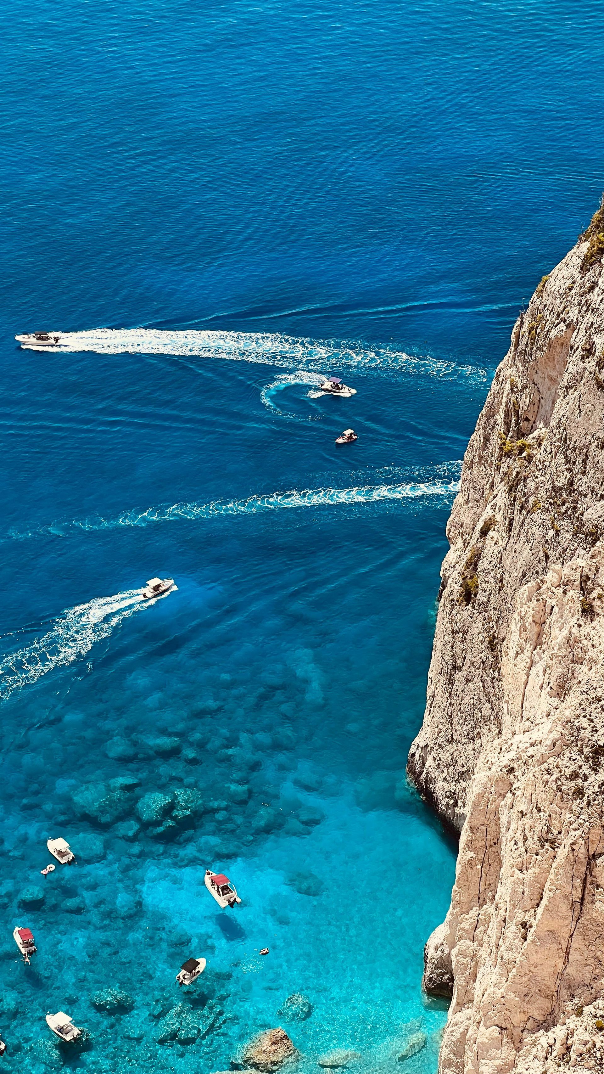 A group of people are swimming in the ocean near a cliff in Zakynthos, Greece.
