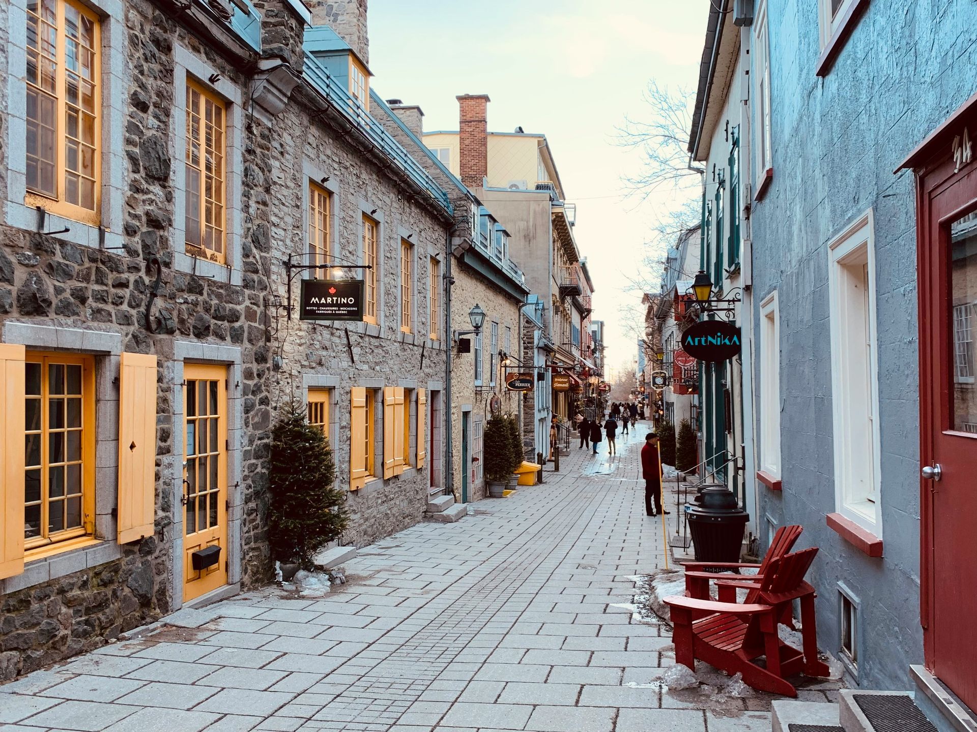 Cobblestone street in Old Quebec, lined with stone buildings featuring colorful doors and shutters.