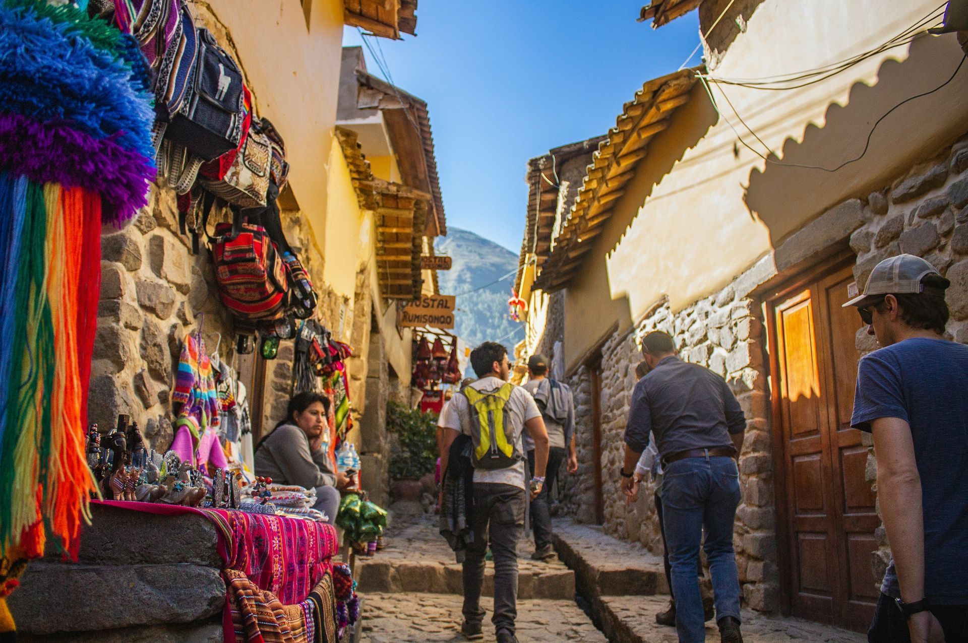 A group of people are walking down a narrow street in Cusco, Peru.