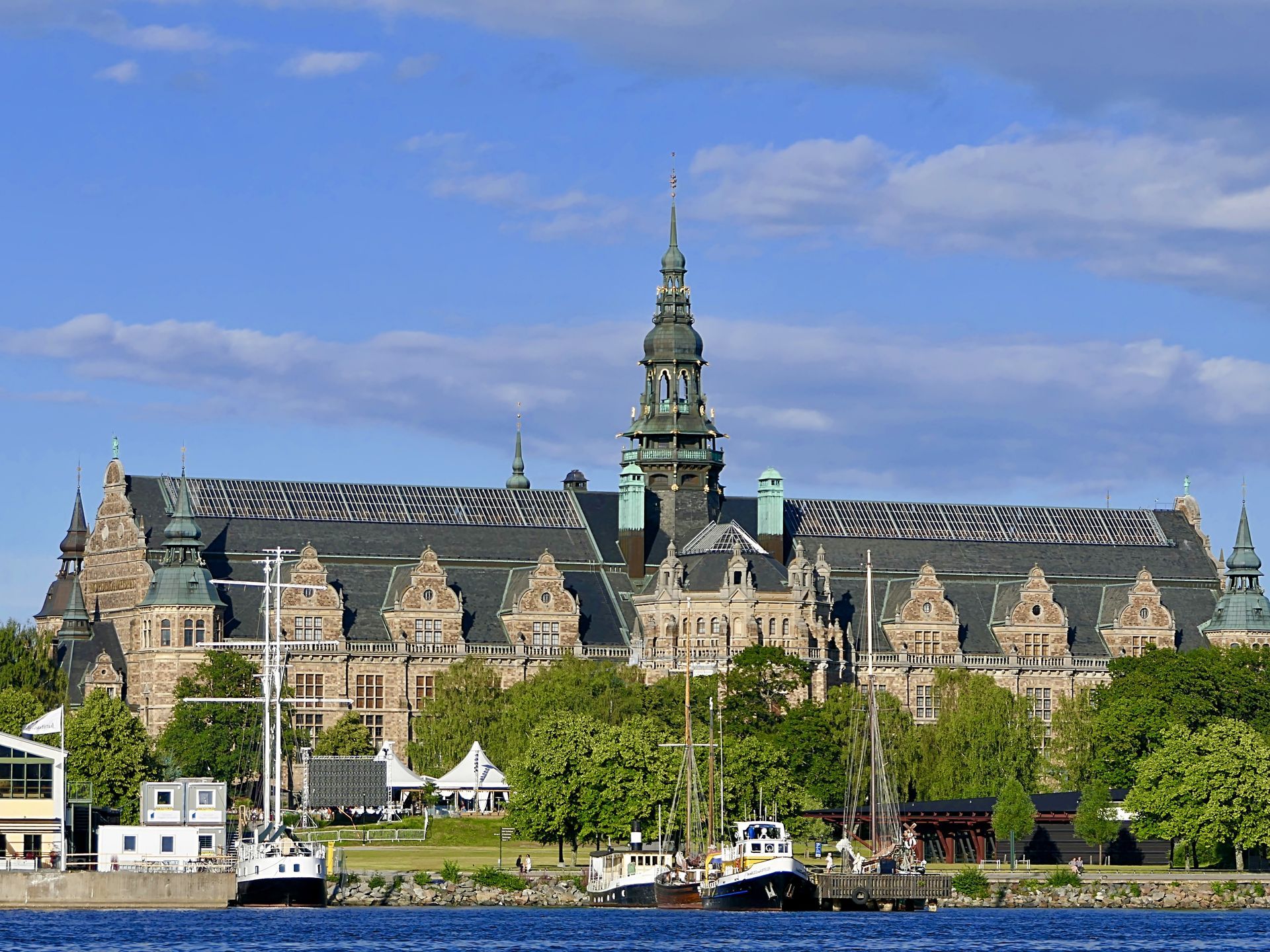 Nordiska Museet with a steeple is next to a body of water in Stockholm.