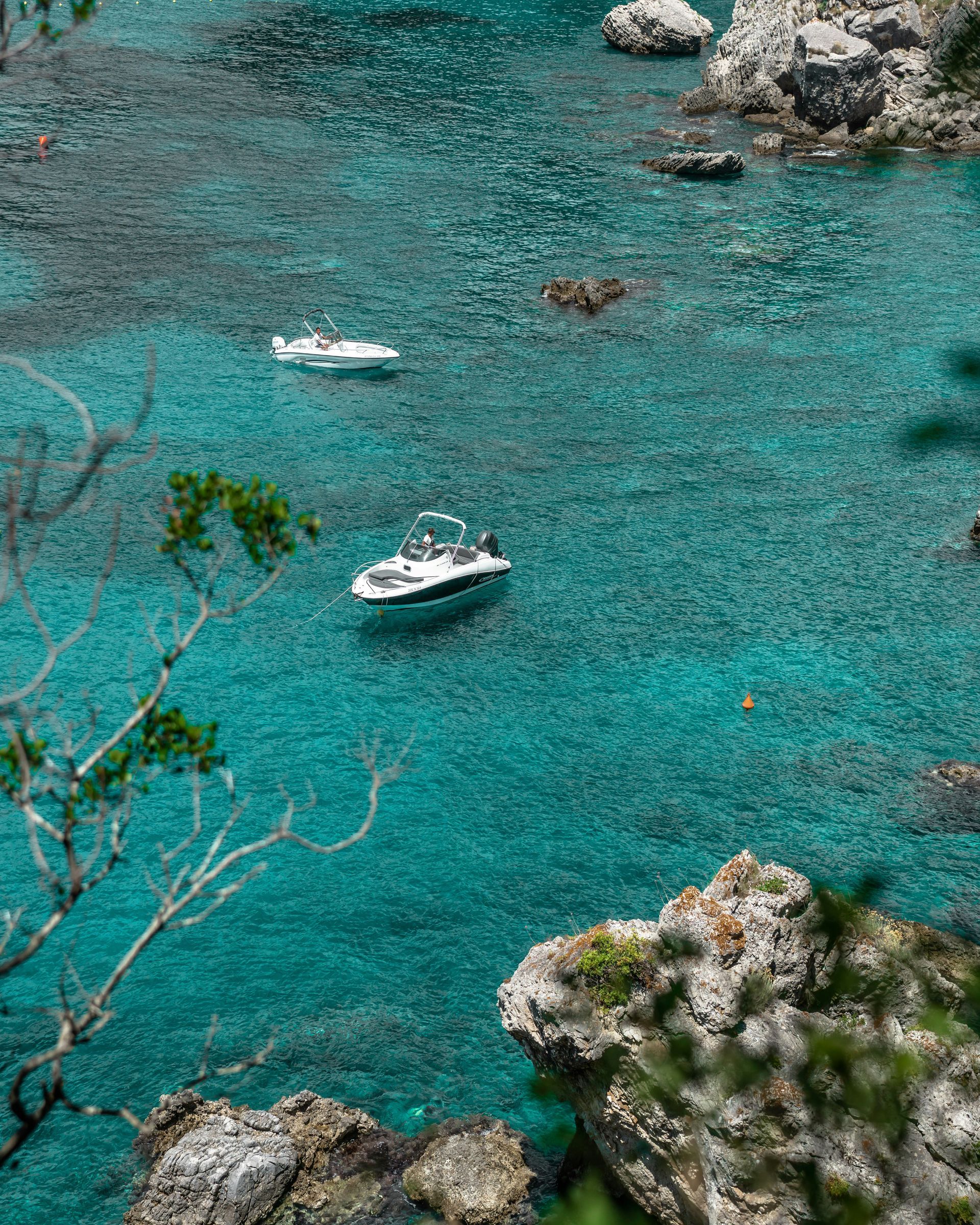A couple of boats are floating on top of a body of water in Corfu, Greece.