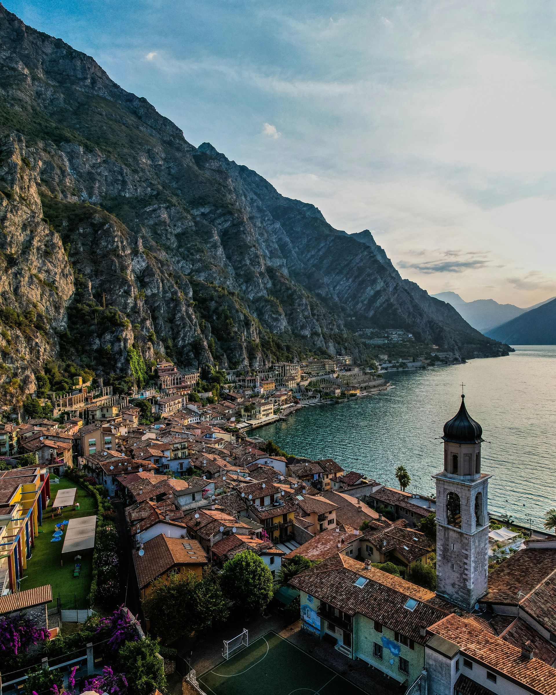 An aerial view of a small town next to Lake Garda with mountains in the background in Italy.