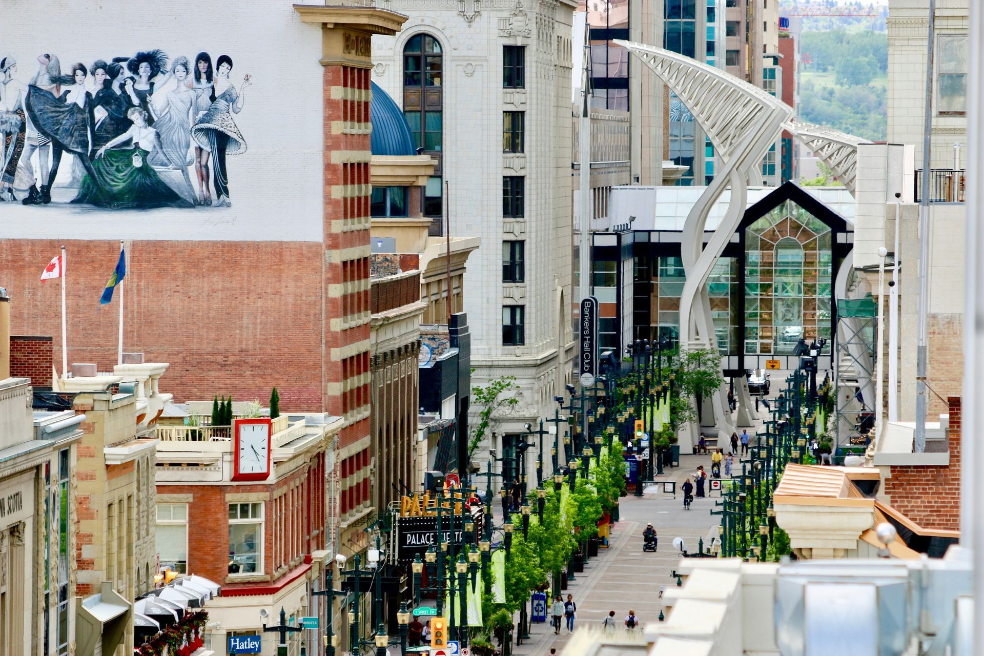 A view of Stephen Avenue Walk in Calgary, Alberta. Tall brick and white buildings line an art-filled pedestrian street.