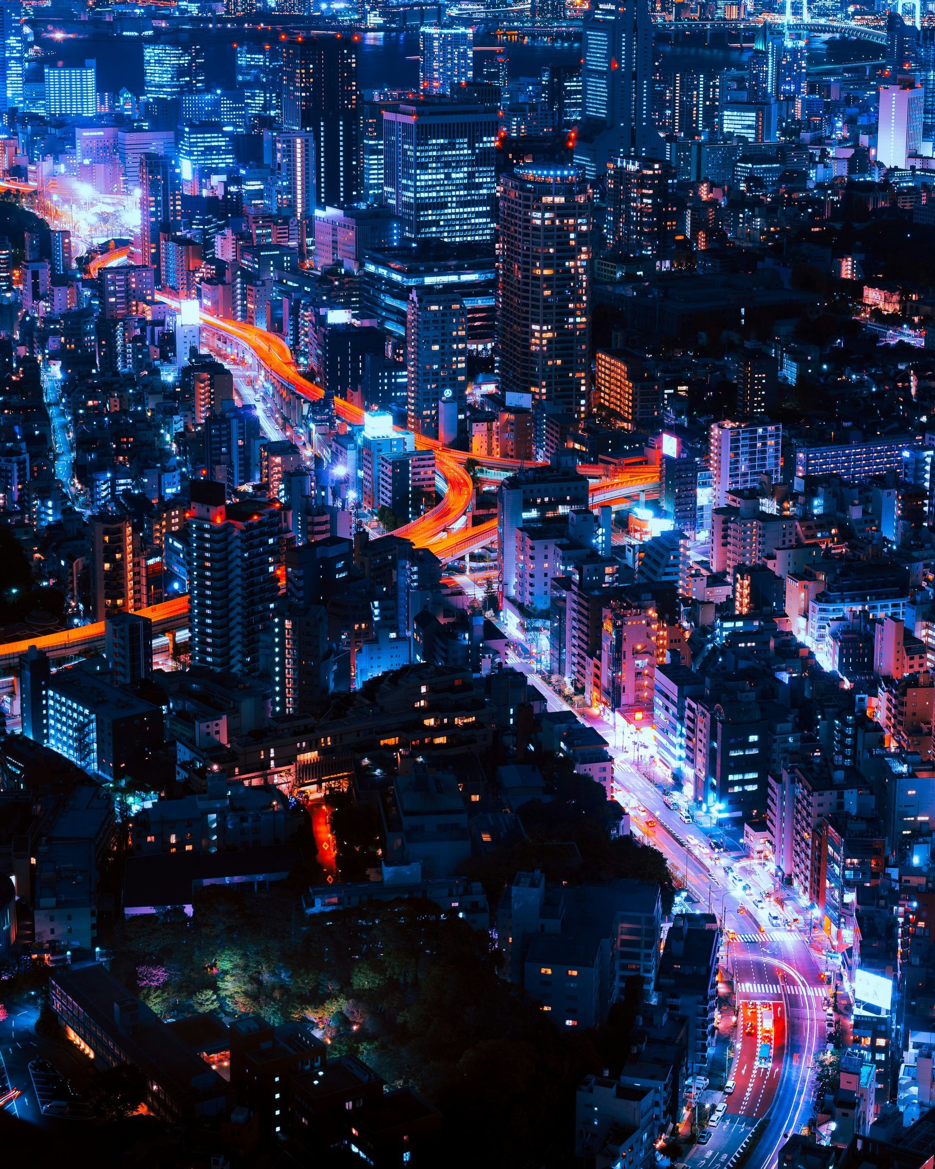 Tokyo, Japan at night, glowing blue and orange lights, buildings, and roads.