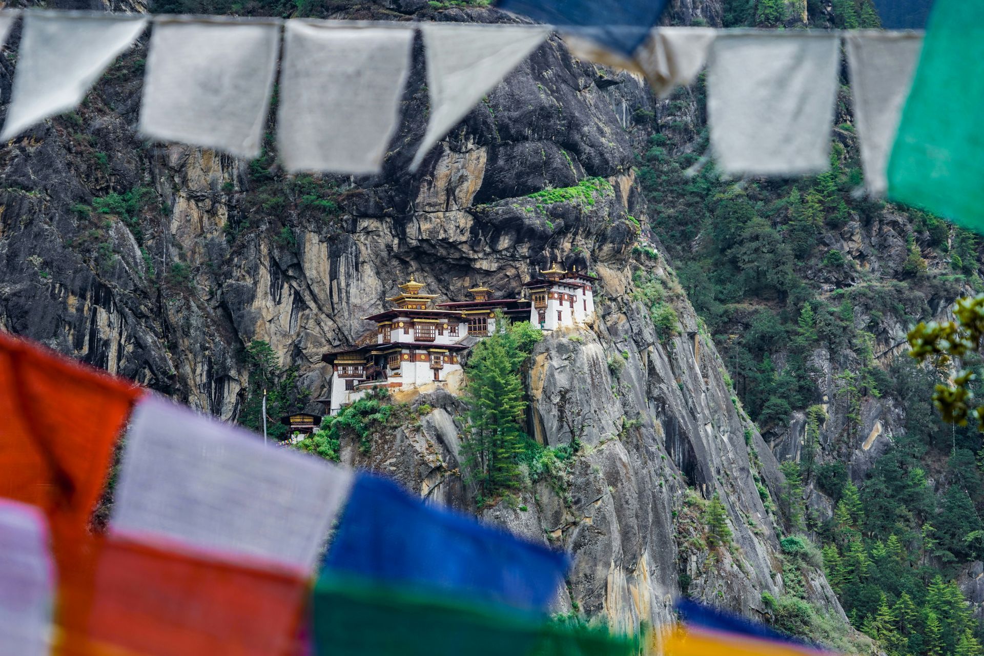 Taktshang Monastery (Tiger's Nest) on a cliffside in Bhutan, with colorful prayer flags in the foreground.