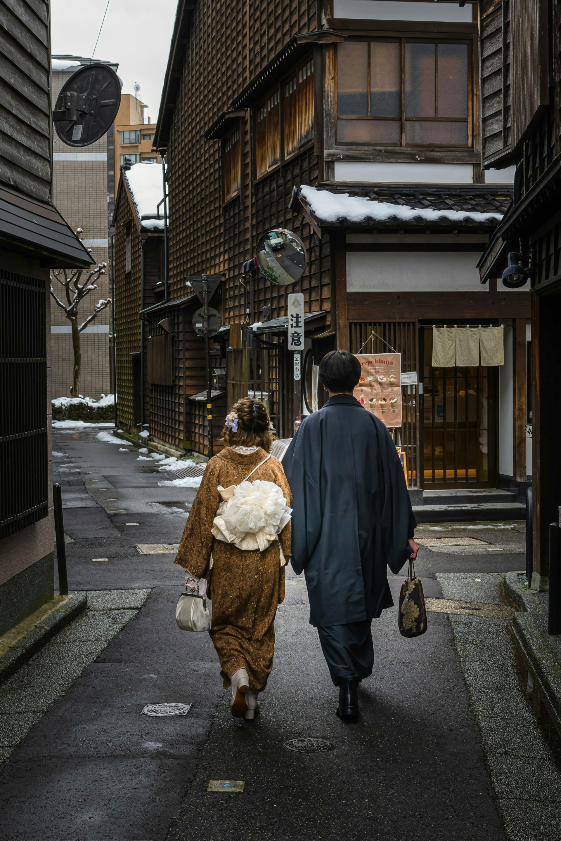 People in traditional Japanese clothing on a narrow street lined with wooden buildings in Kanazawa, Japan.