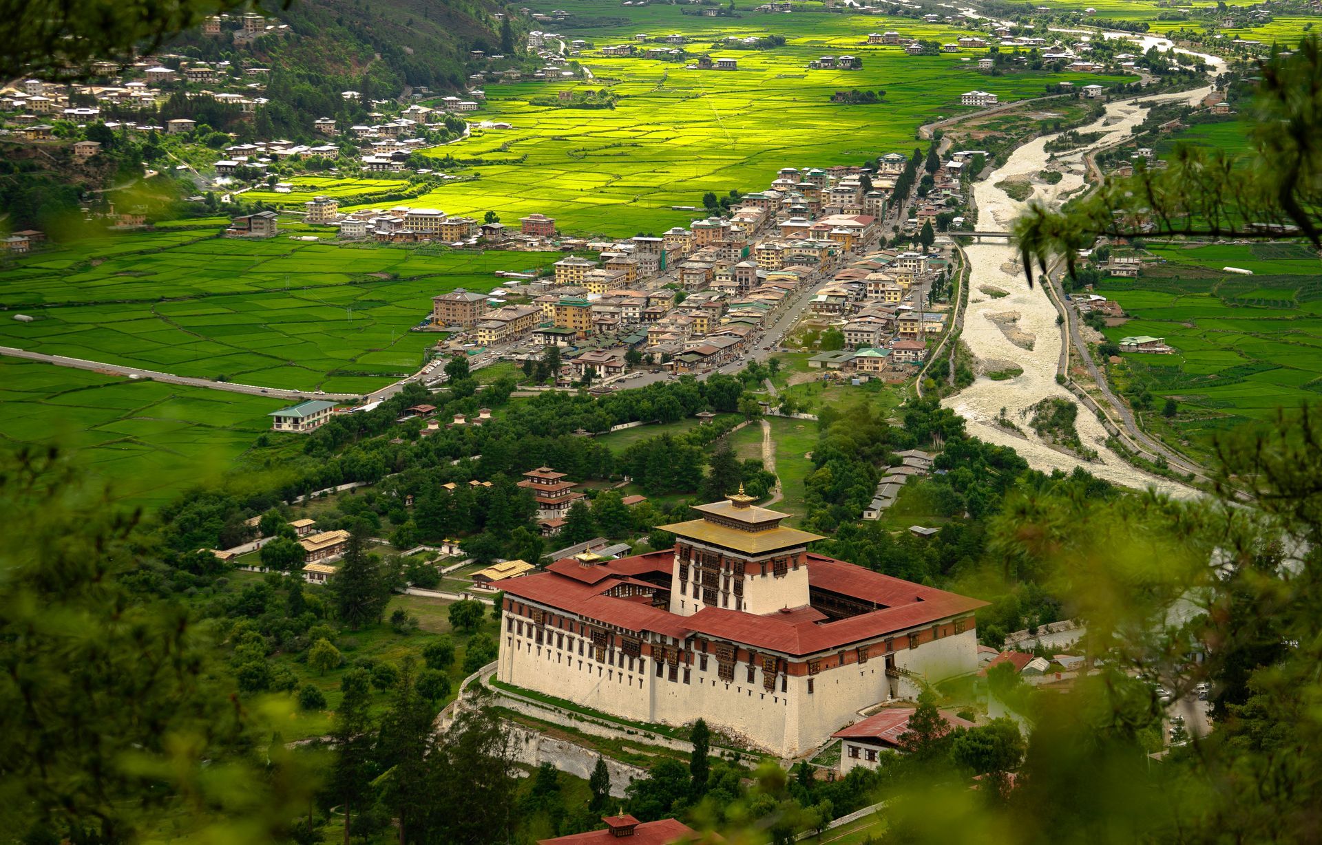 Rinpung Dzong in a valley, river and town of Paro in the background, green fields and trees in Bhutan.