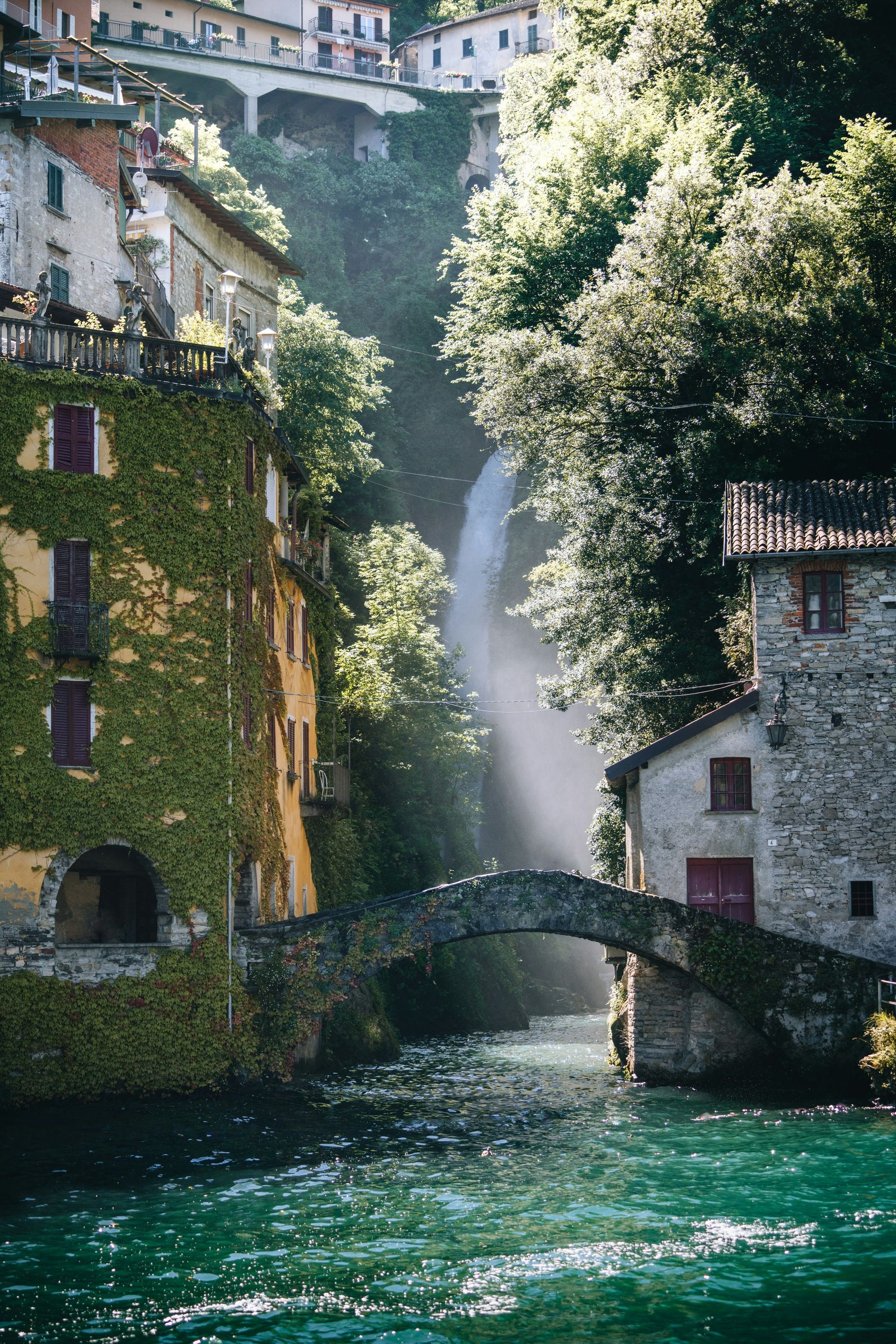 A bridge over Lake Como with a waterfall in the background in Italy.