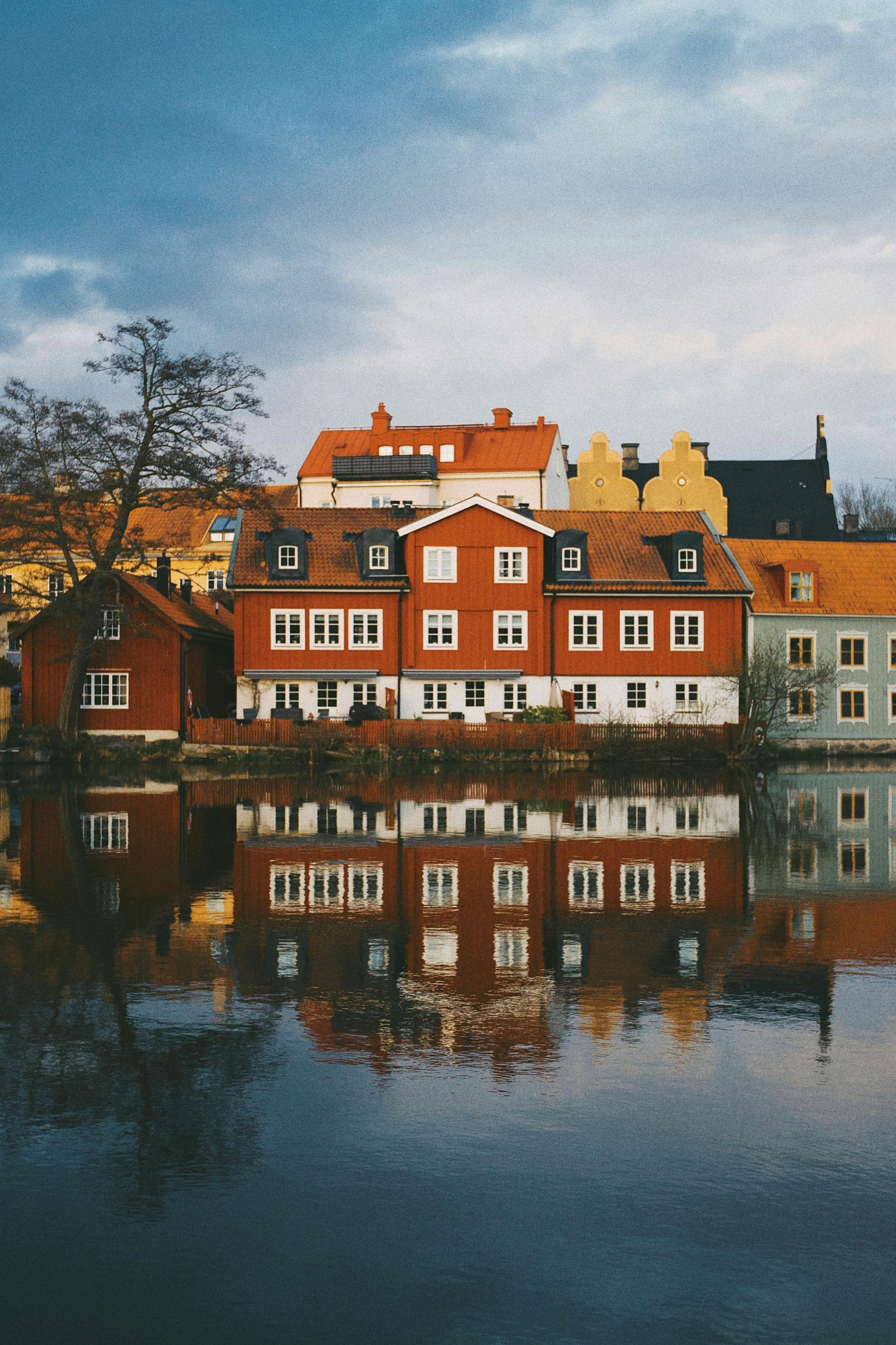 A group of buildings are reflected in a body of water in Stockholm.