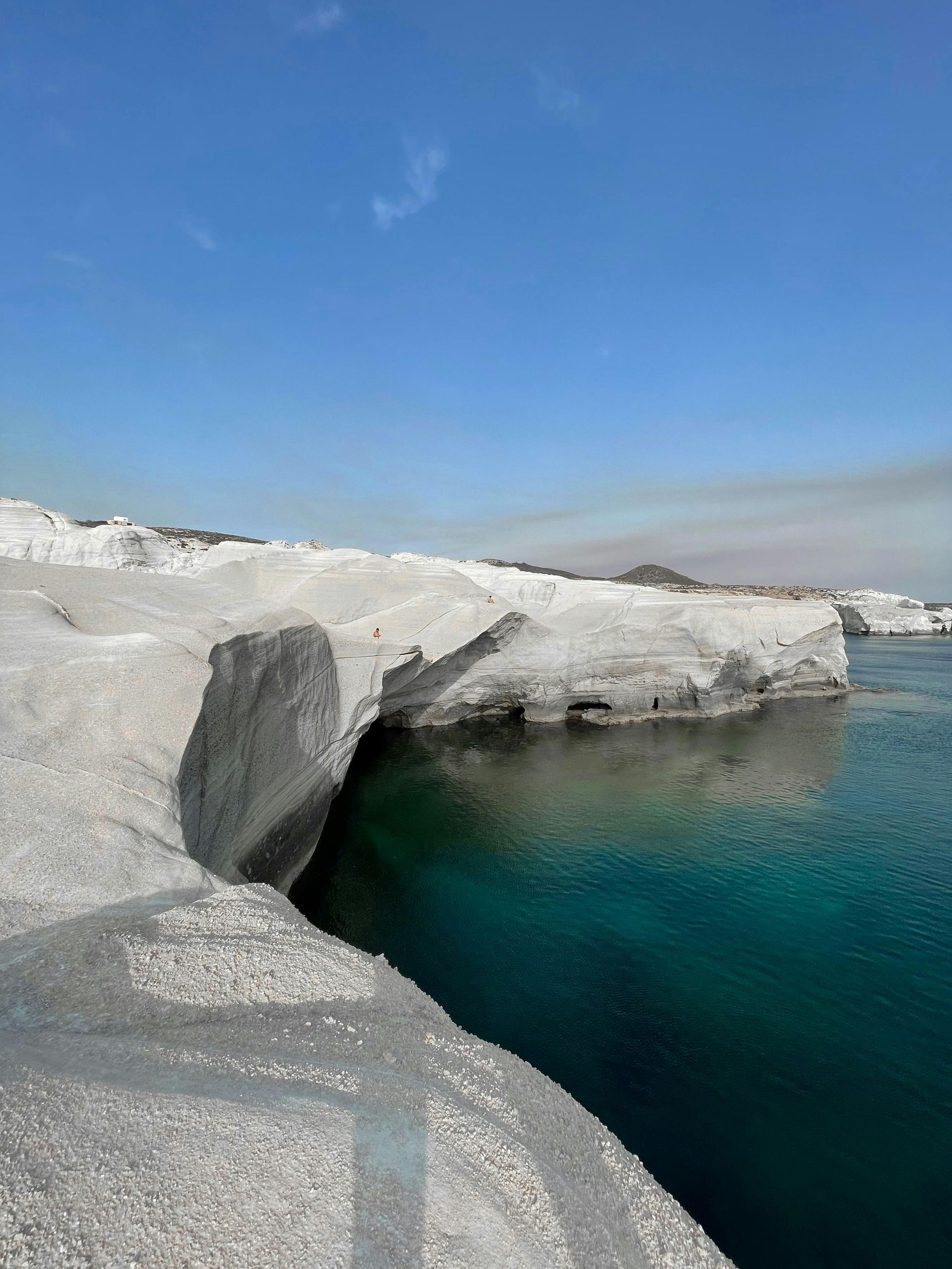 A large rock is sitting on the edge of Sarakiniko Beach in Milos, Greece.