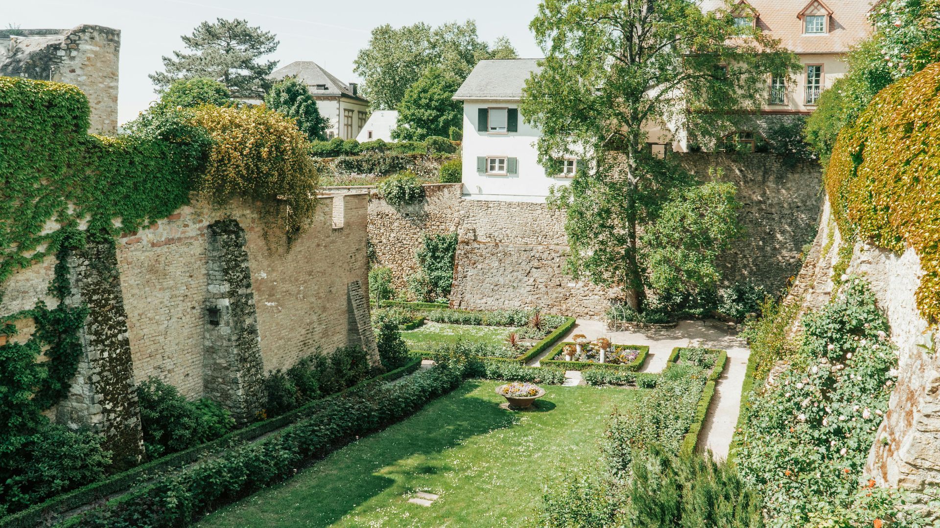 A garden with a stone wall and a house in the background in Eltville, Germany.