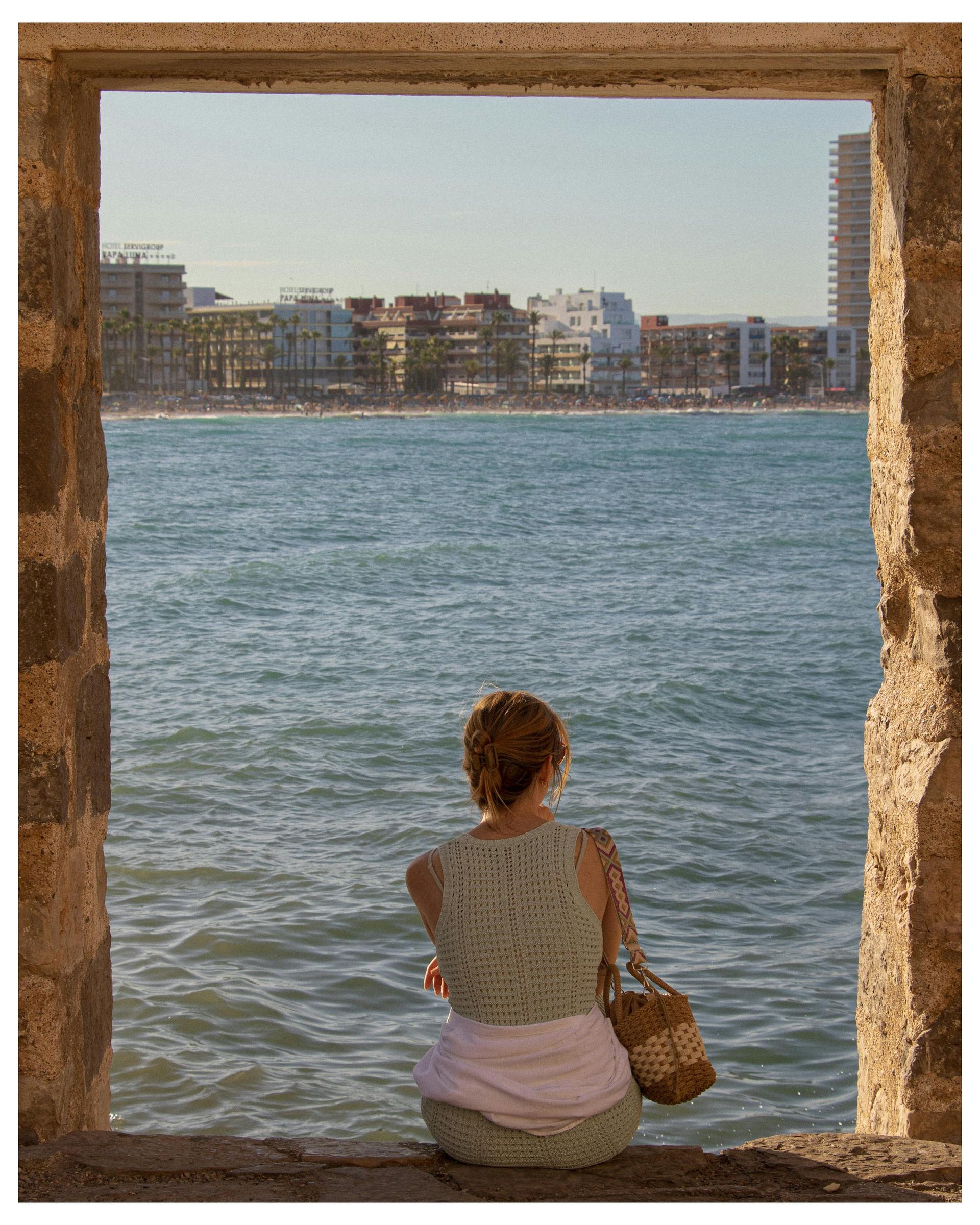 A woman is looking out over the ocean through a window