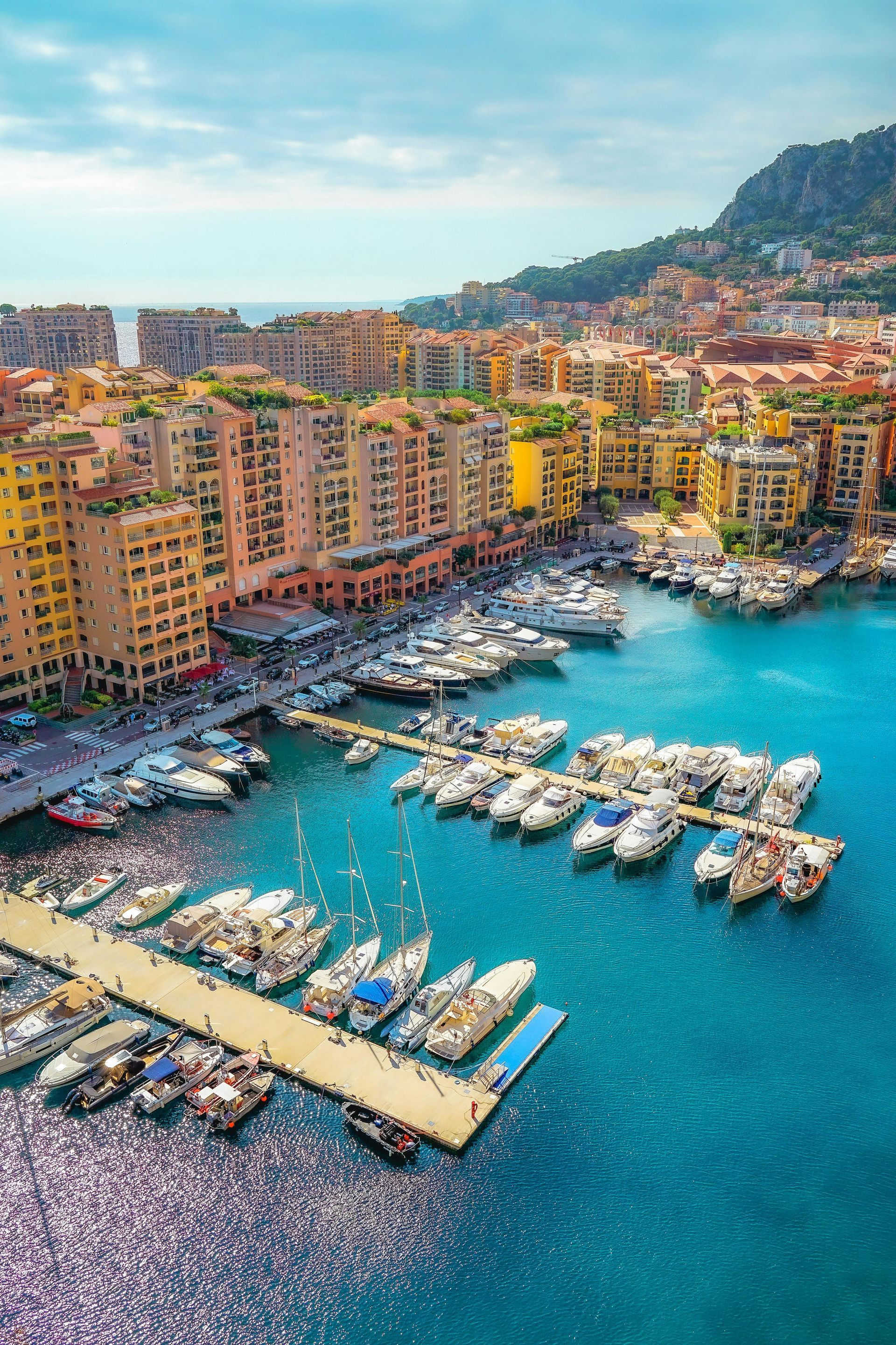 An aerial view of a marina with boats docked and buildings in the background in Monaco.