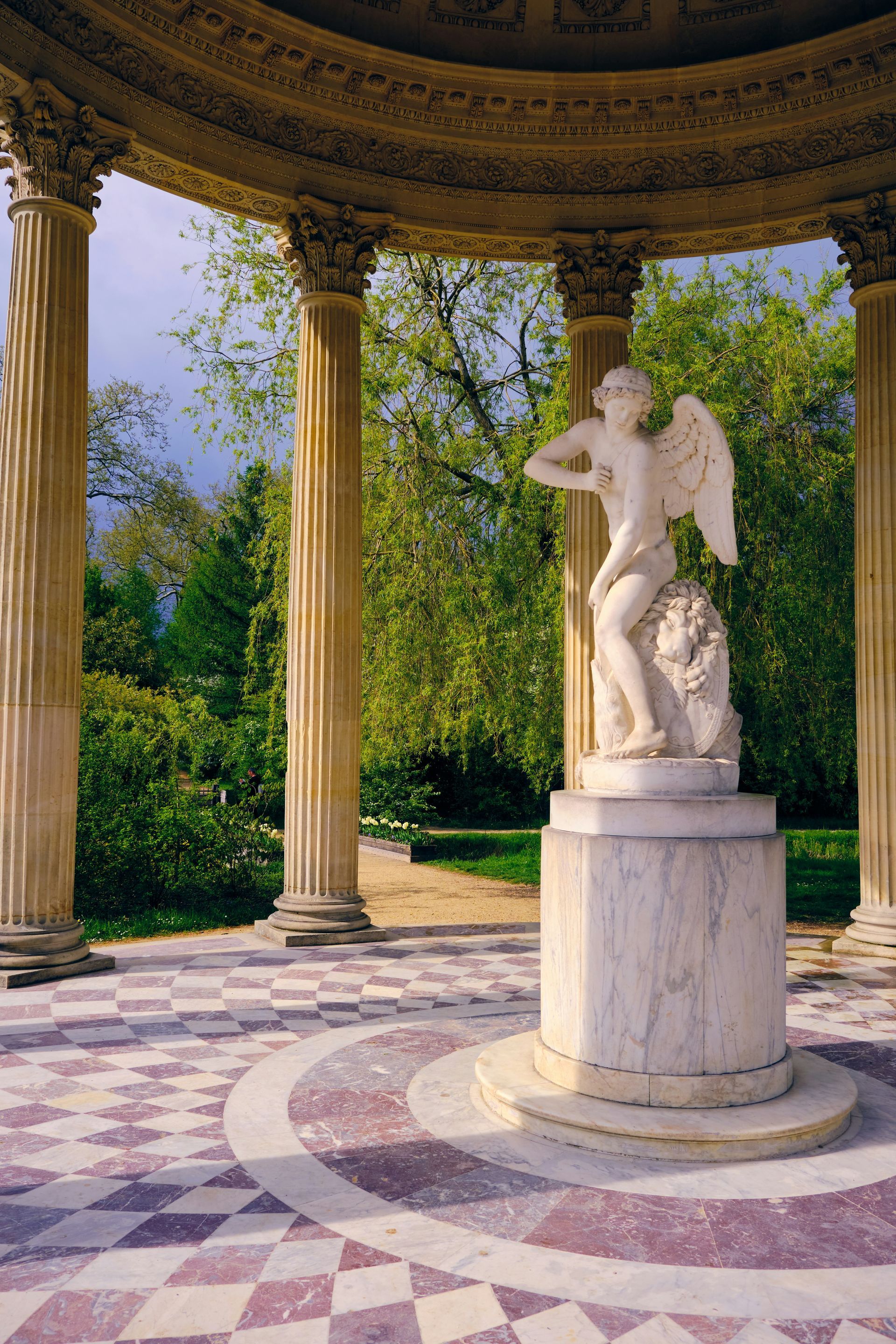 A statue of a man with wings standing under a gazebo at the Palace of Versailles in France.
