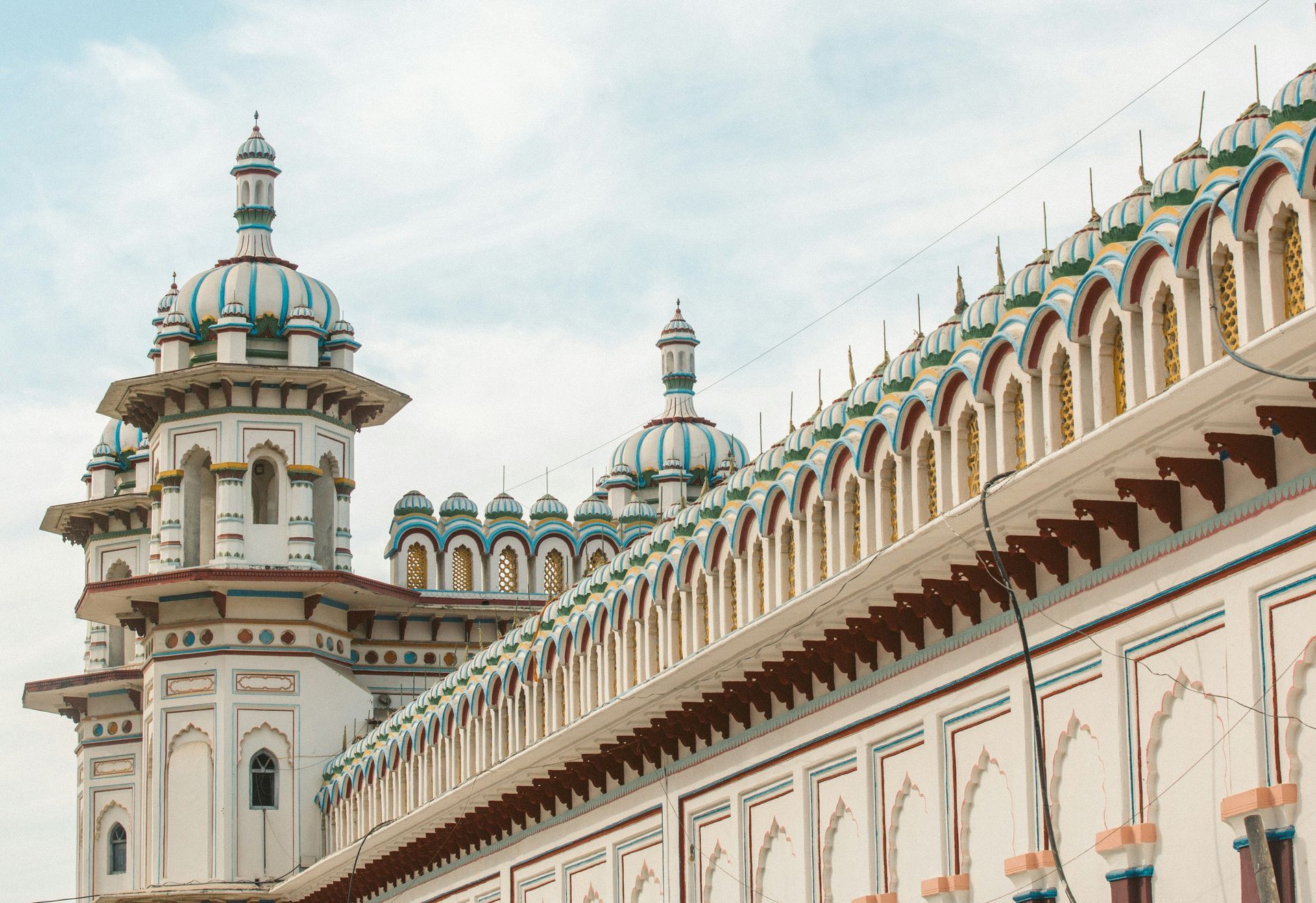 Ornate white and teal temple with multiple domes in Janakpur, Nepal.