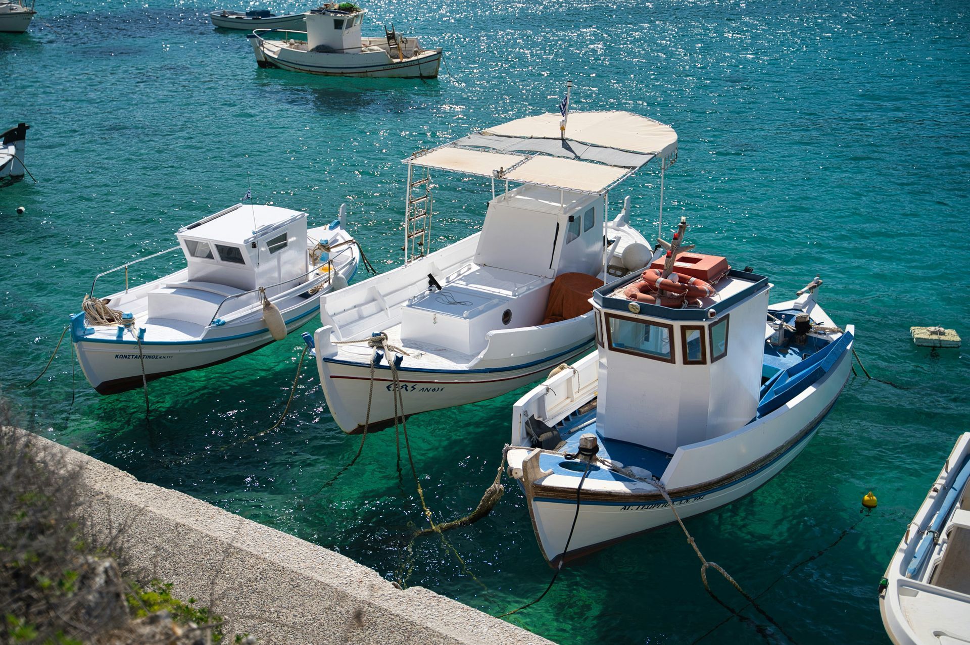 Three boats are tied to a dock in the water in Paros, Greece.