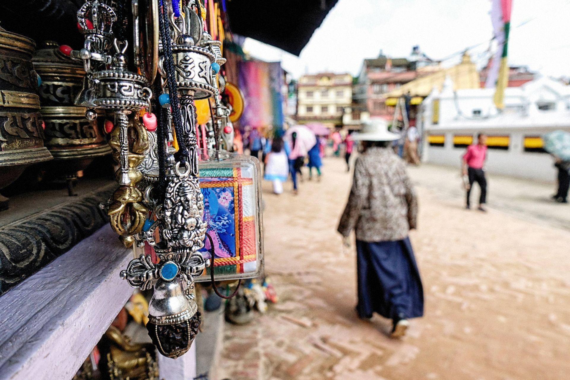 Market stall with jewelry in focus, blurred people walking on a path in Kathmandu, Nepal.