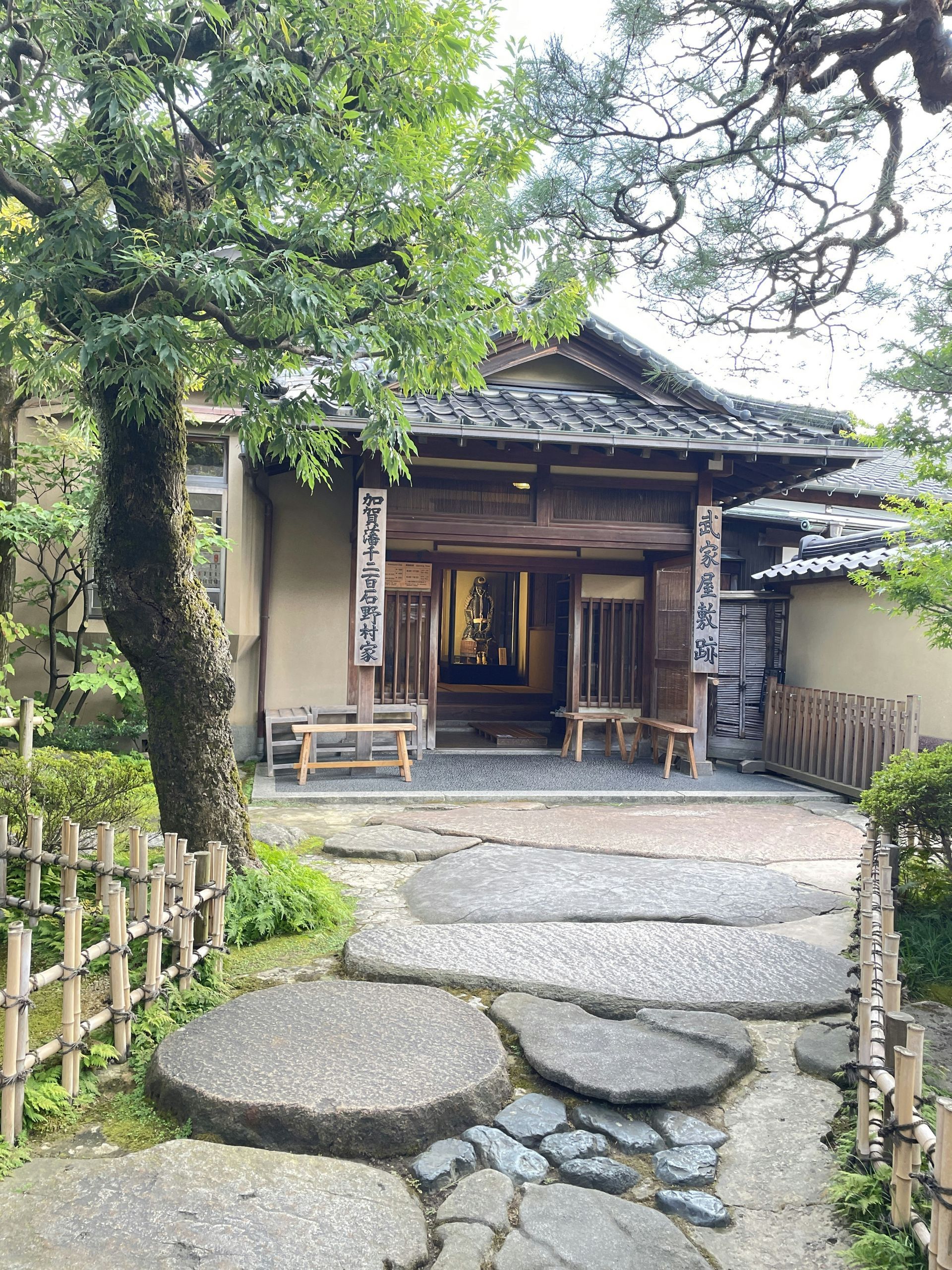 Stone path leading to a traditional Japanese building in Kanazawa, Japan, with a wooden entrance and a bamboo fence.