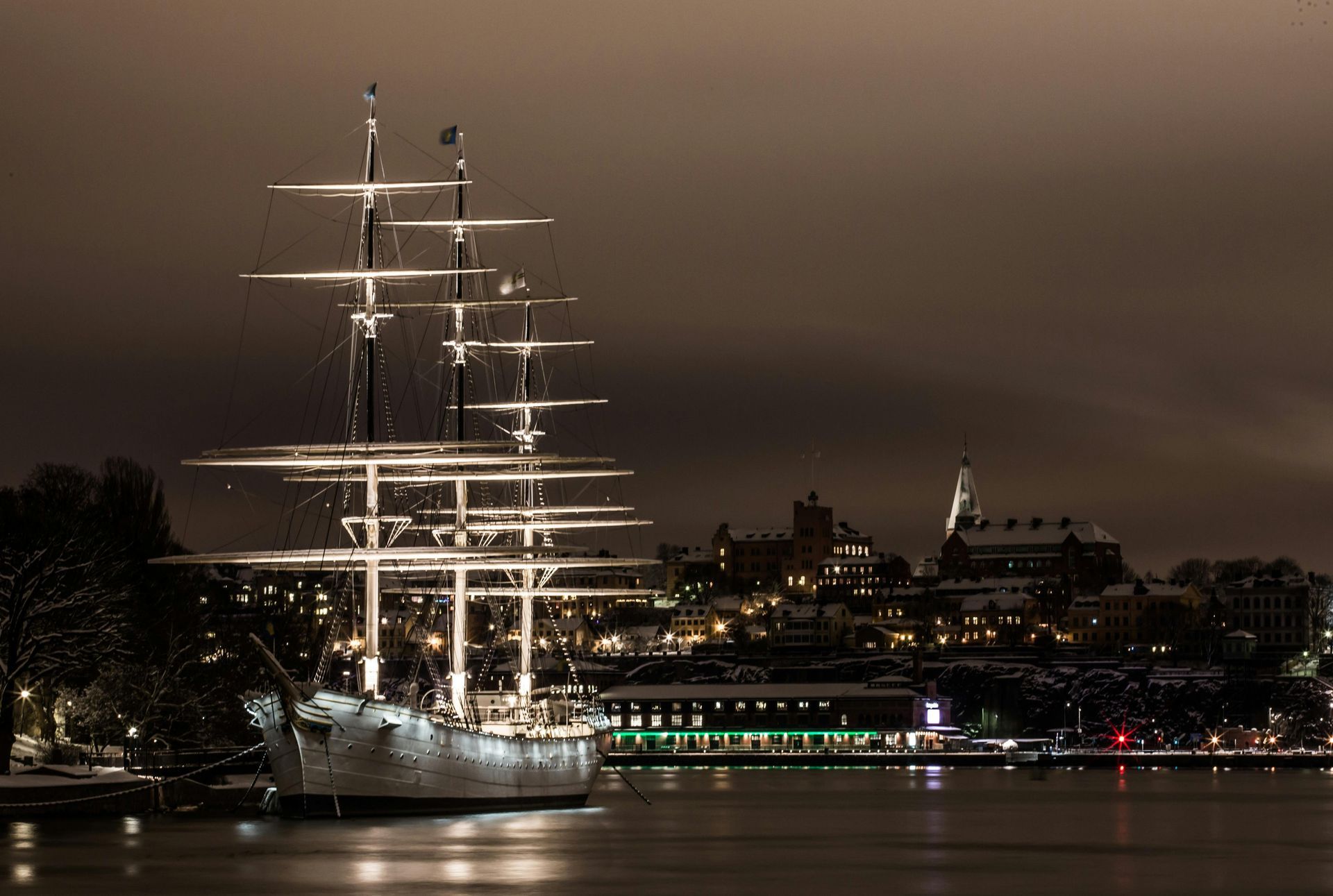 A large sailboat is docked in a harbor at night in Stockholm.