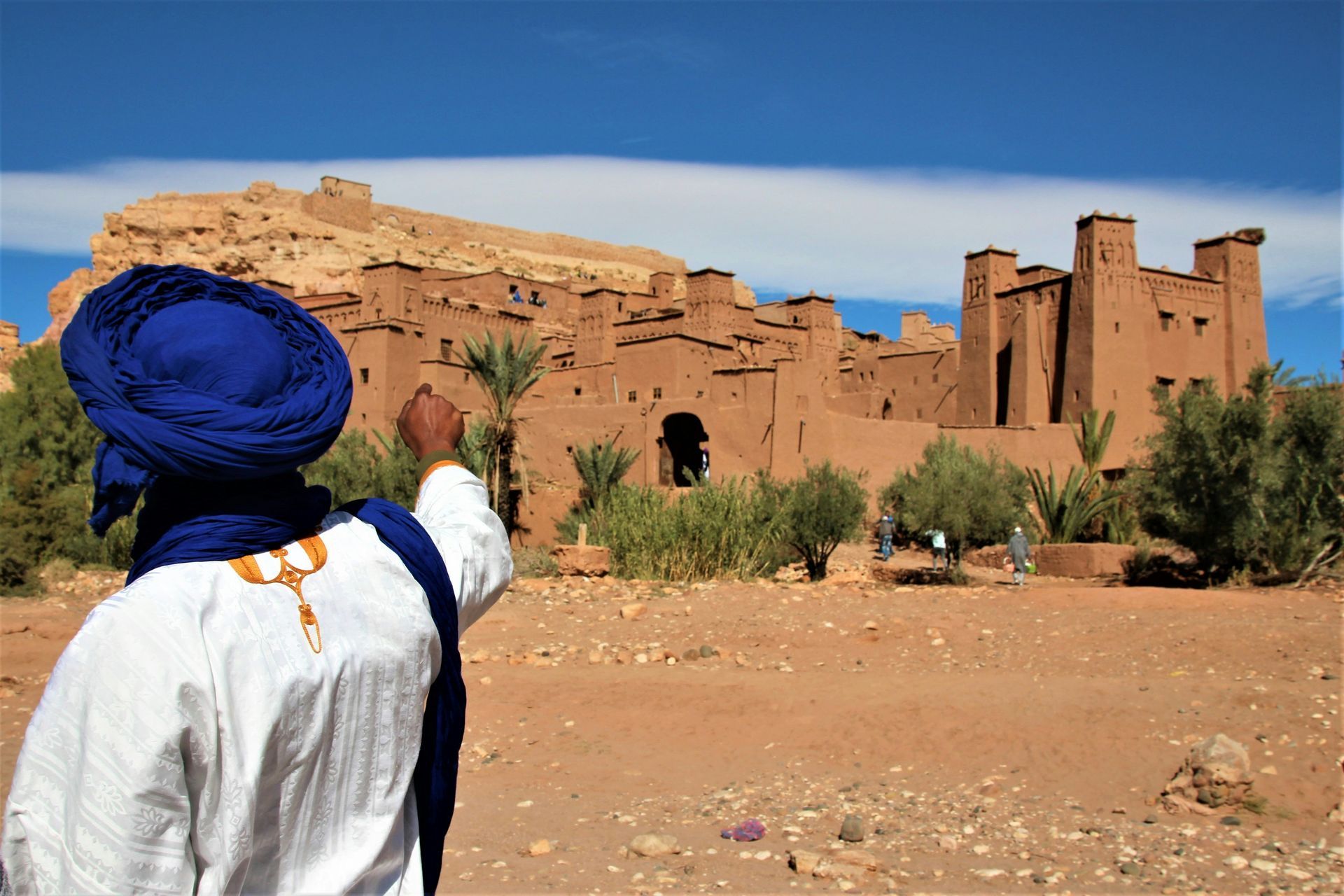 A man in a blue turban is standing in front of the city of Ouarzazate, Morocco.