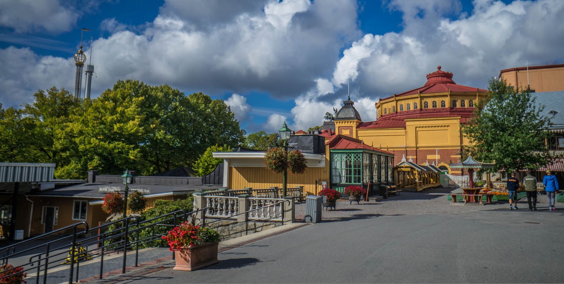 A group of people are walking down a street next to Skansen in Stockholm.
