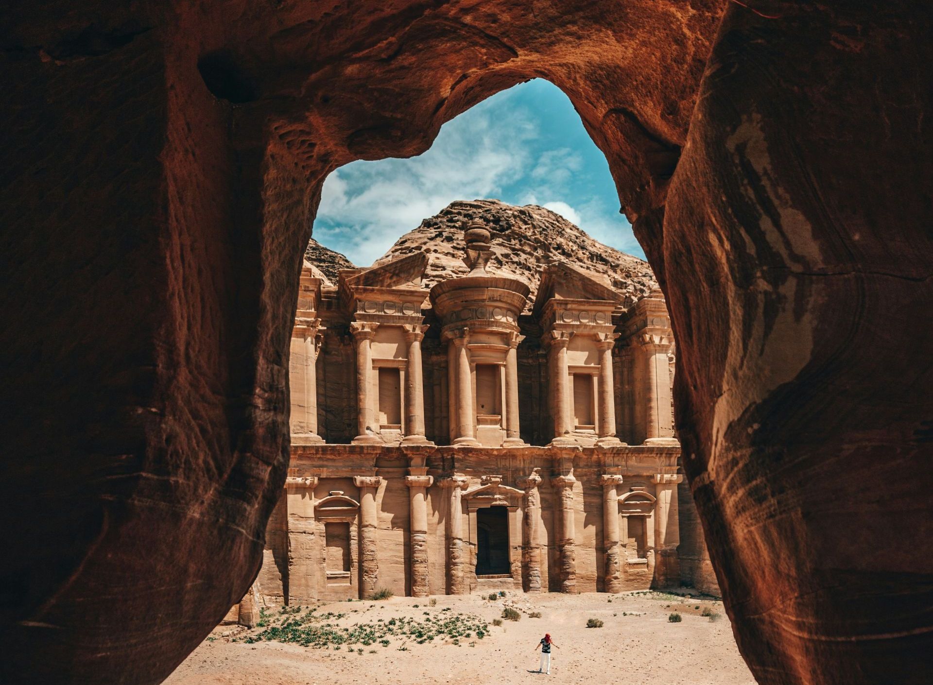 A view of a building built into a cliff through a cave in the desert of Jordan.