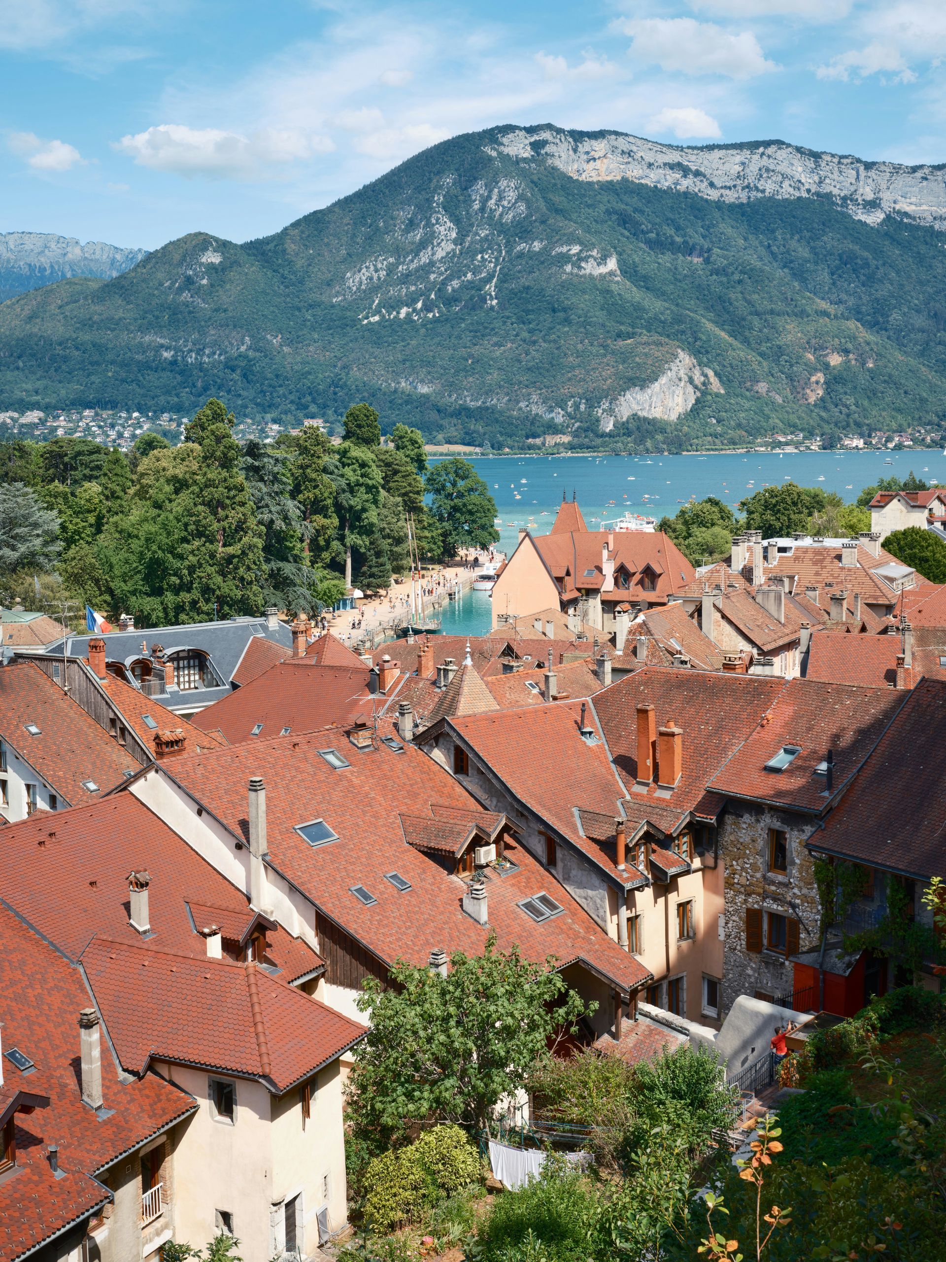 An aerial view of a city with mountains in the background and Lake Annecy in the foreground in France.