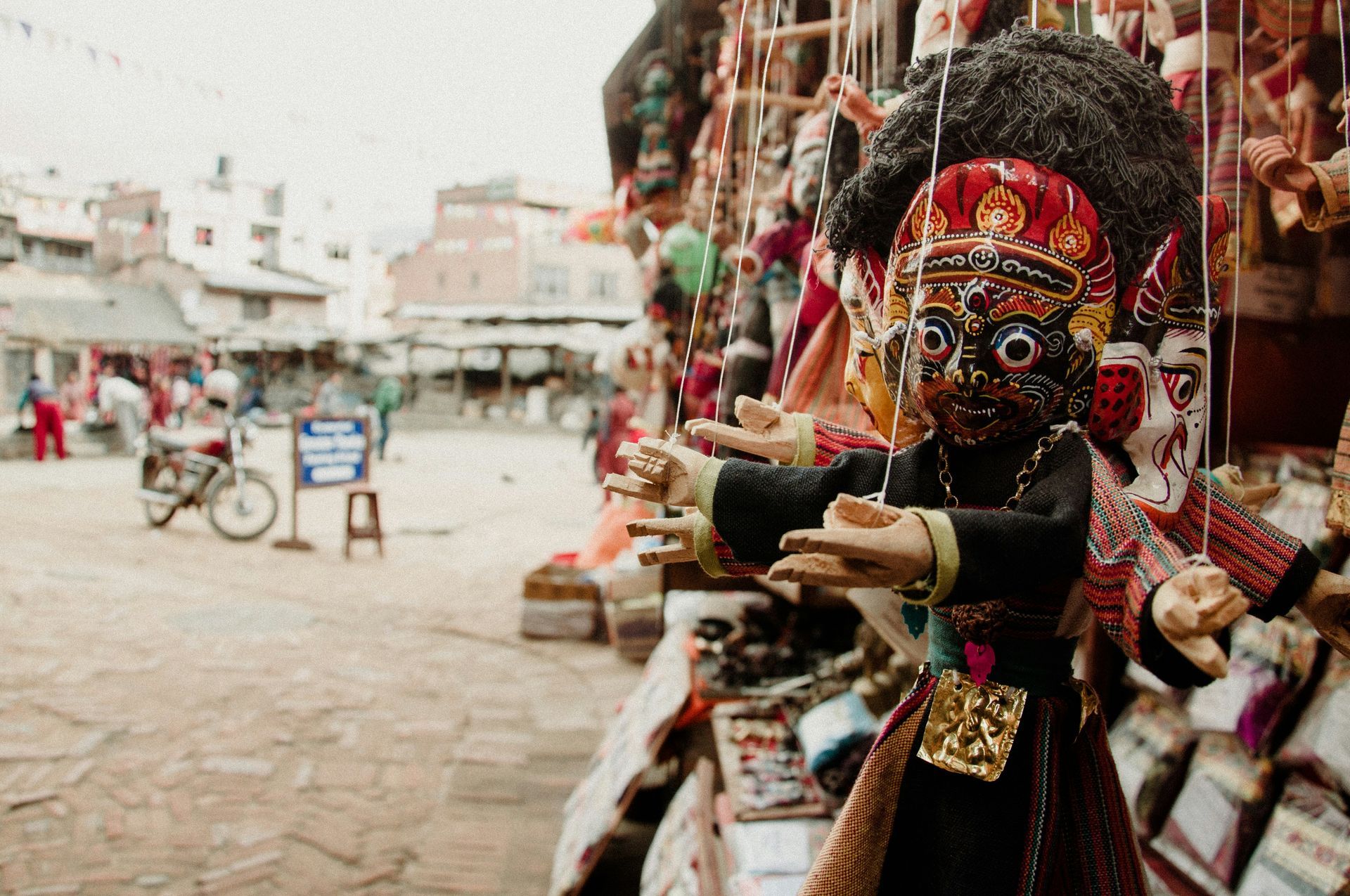 Puppet with intricate details hangs in front of a street market in Bhaktapur, Nepal.