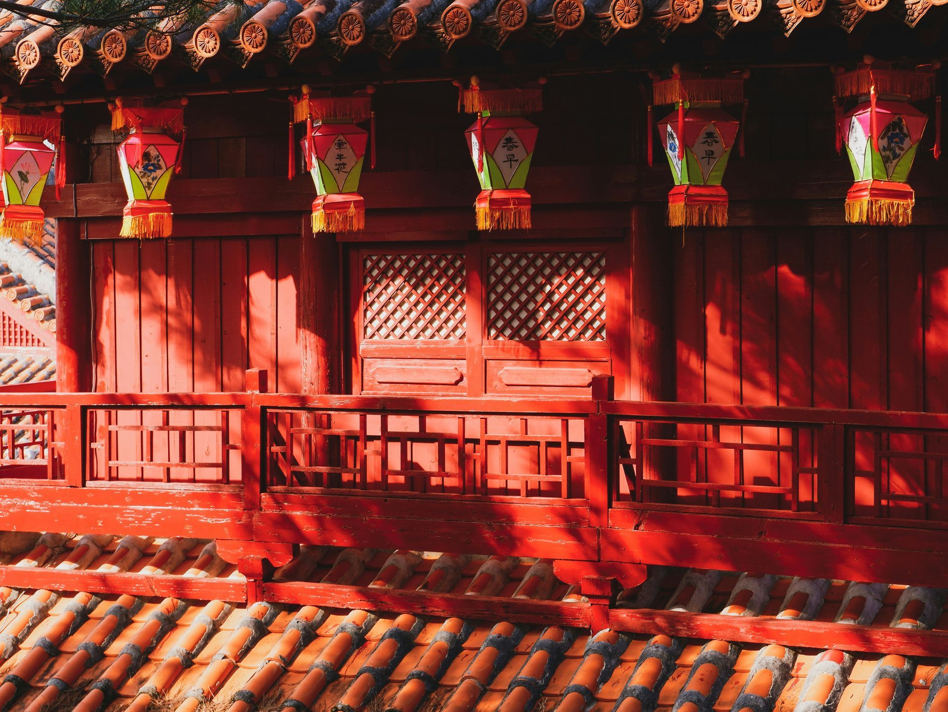 Red traditional Asian building with lanterns hanging, tiled roof in Okinawa, Japan.