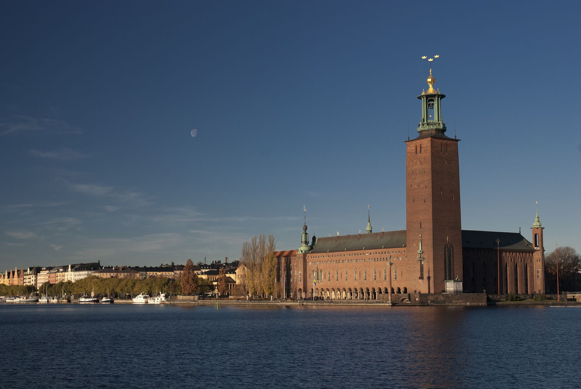 Stockholm City Hall with a clock tower is next to a body of water in Sweden.