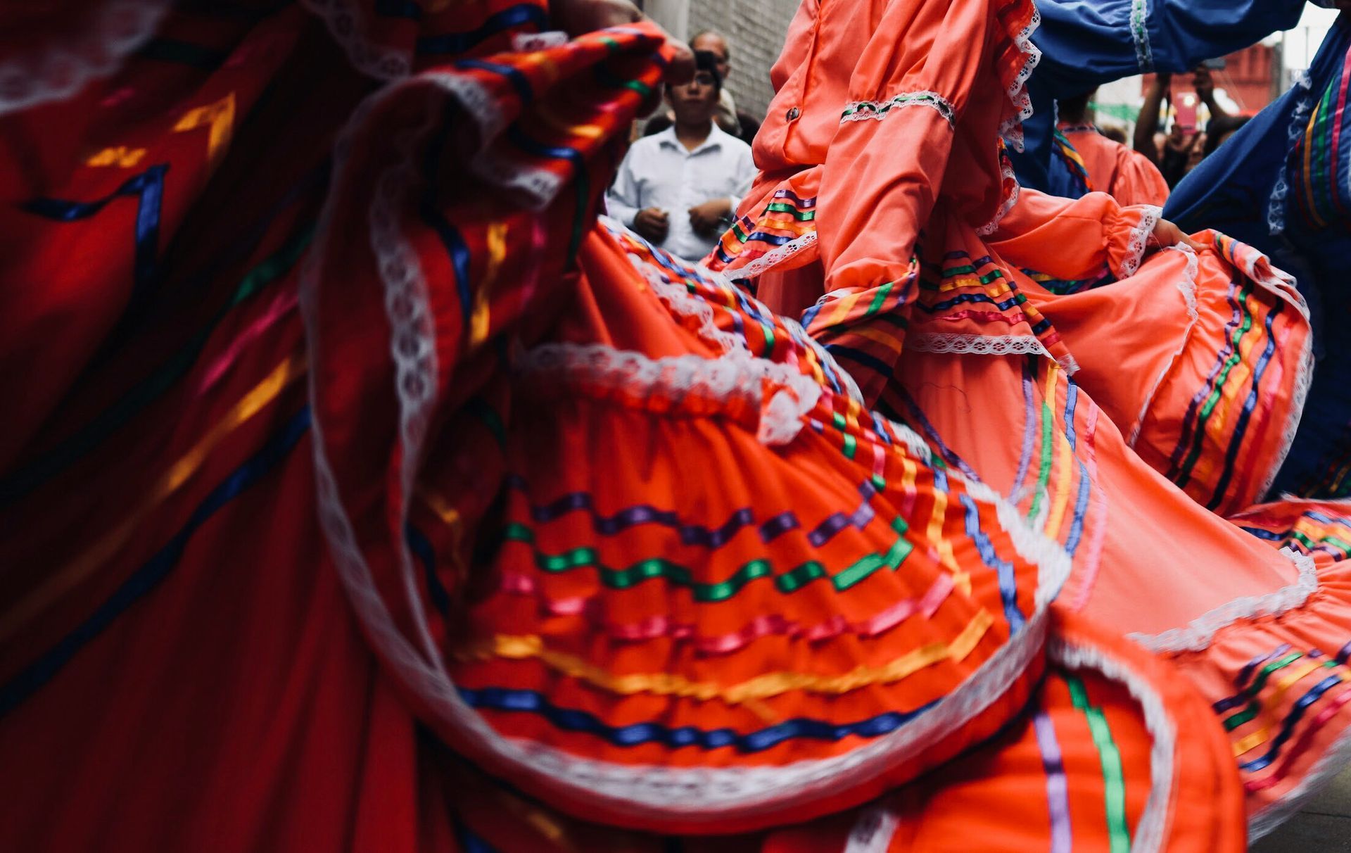Close-up of dancers in bright red dresses with colorful ribbons in Mexico.