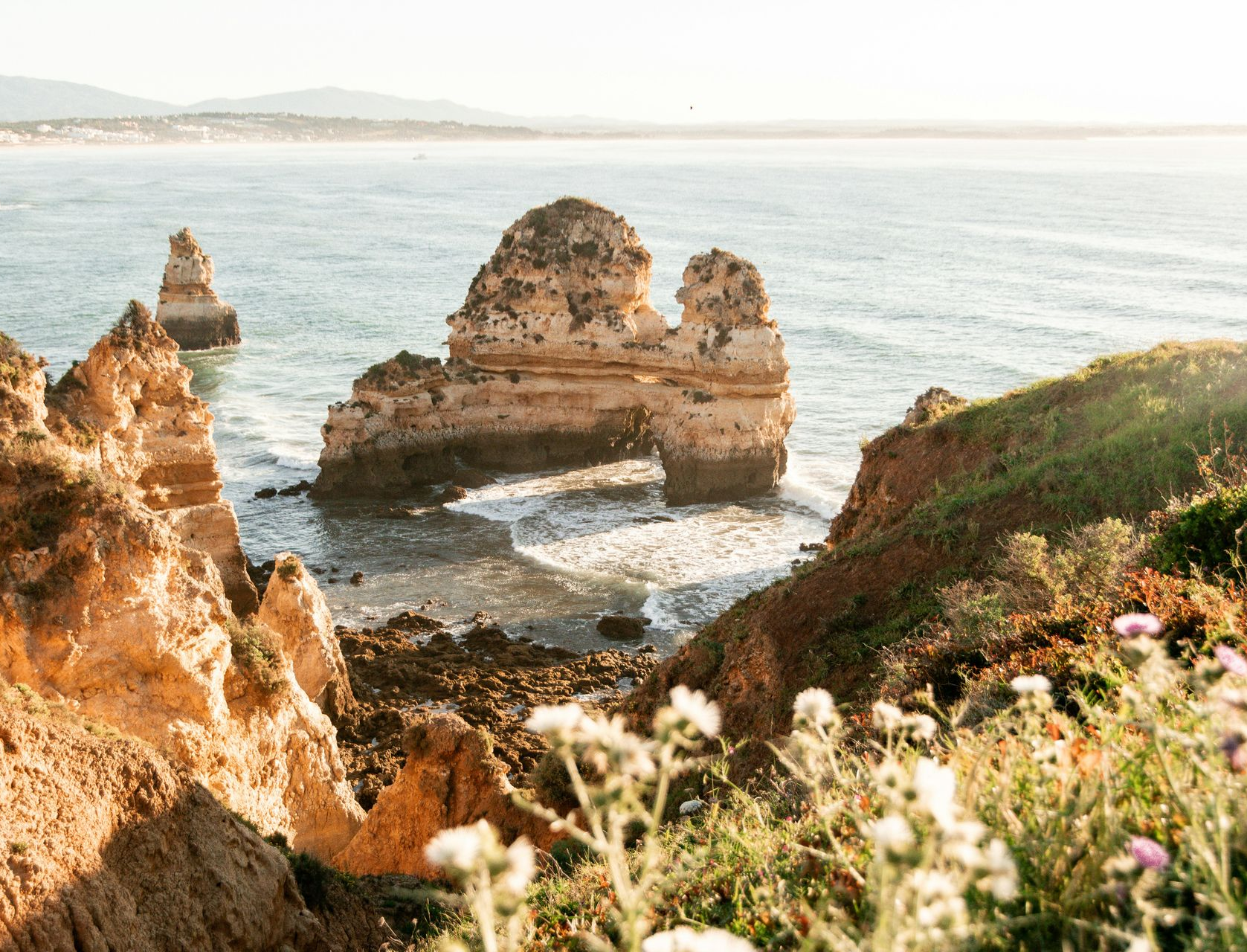 Coastal cliffs with rock formations in the ocean; sunny day in the Algarve, Portugal.